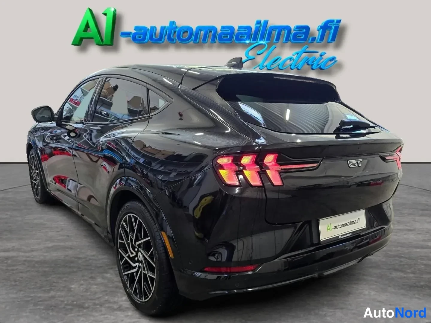 Takaviisto: Musta Ford Mustang Mach-E takanurkka vasemmalta, kolmiosaiset takavalot ja GT-merkki näkyvät.