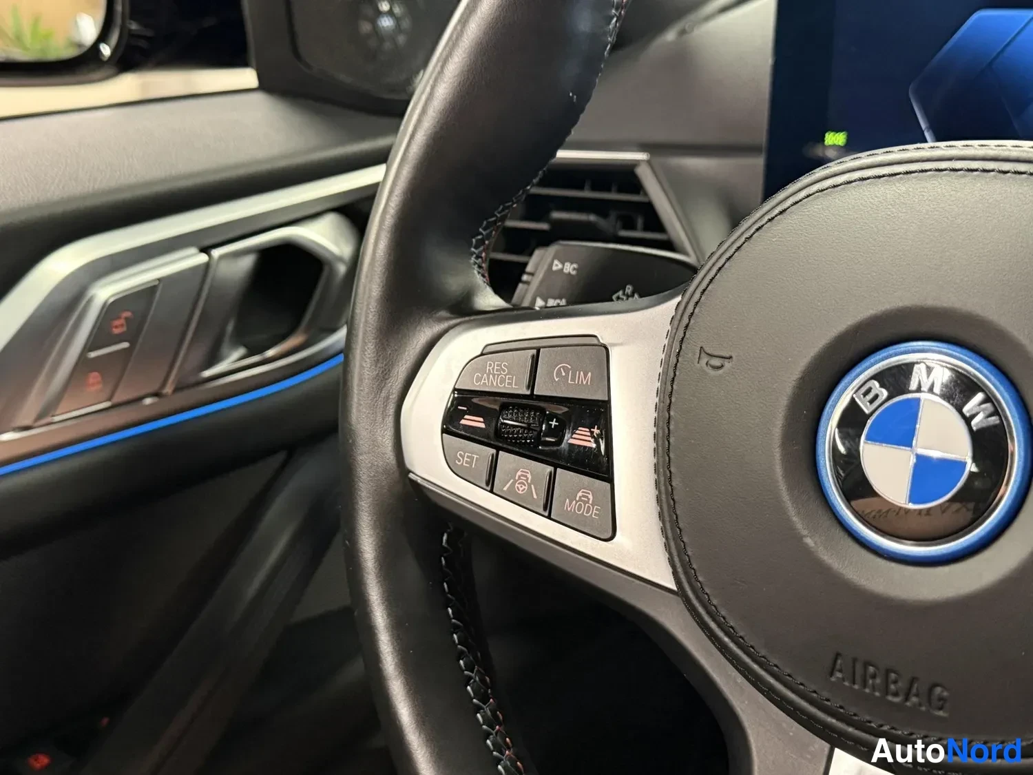Muu: BMW-ohjauspyörän vasemman puolen painikkeet ja merkki, taustalla kojelautaa.