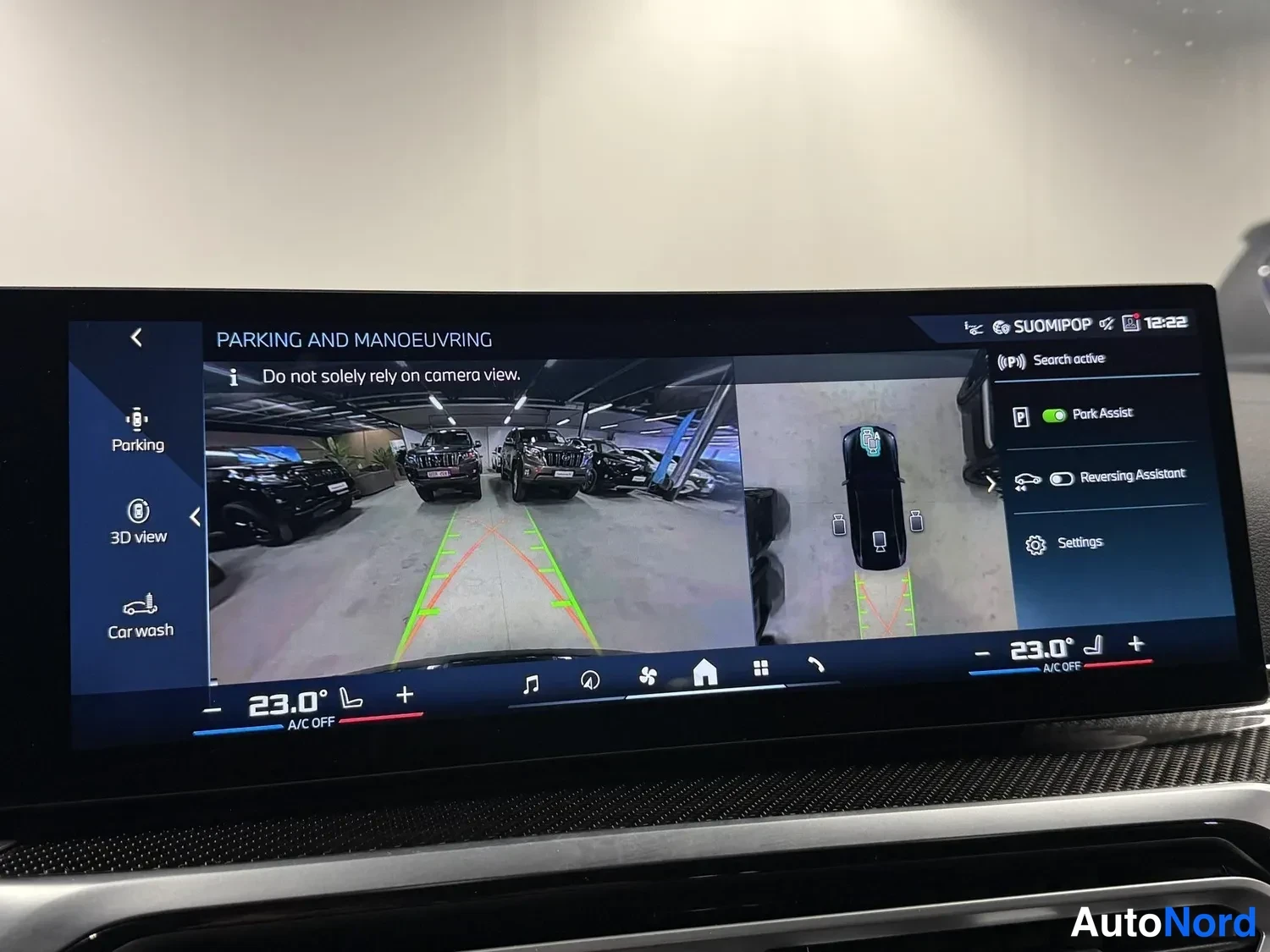 Muu: Näytössä 'PARKING AND MANOEUVRING' -valikko: peruutuskamerakuvaa, Park Assist ja Reversing Assistant, lämpötila 23,0°, kello 12:22.