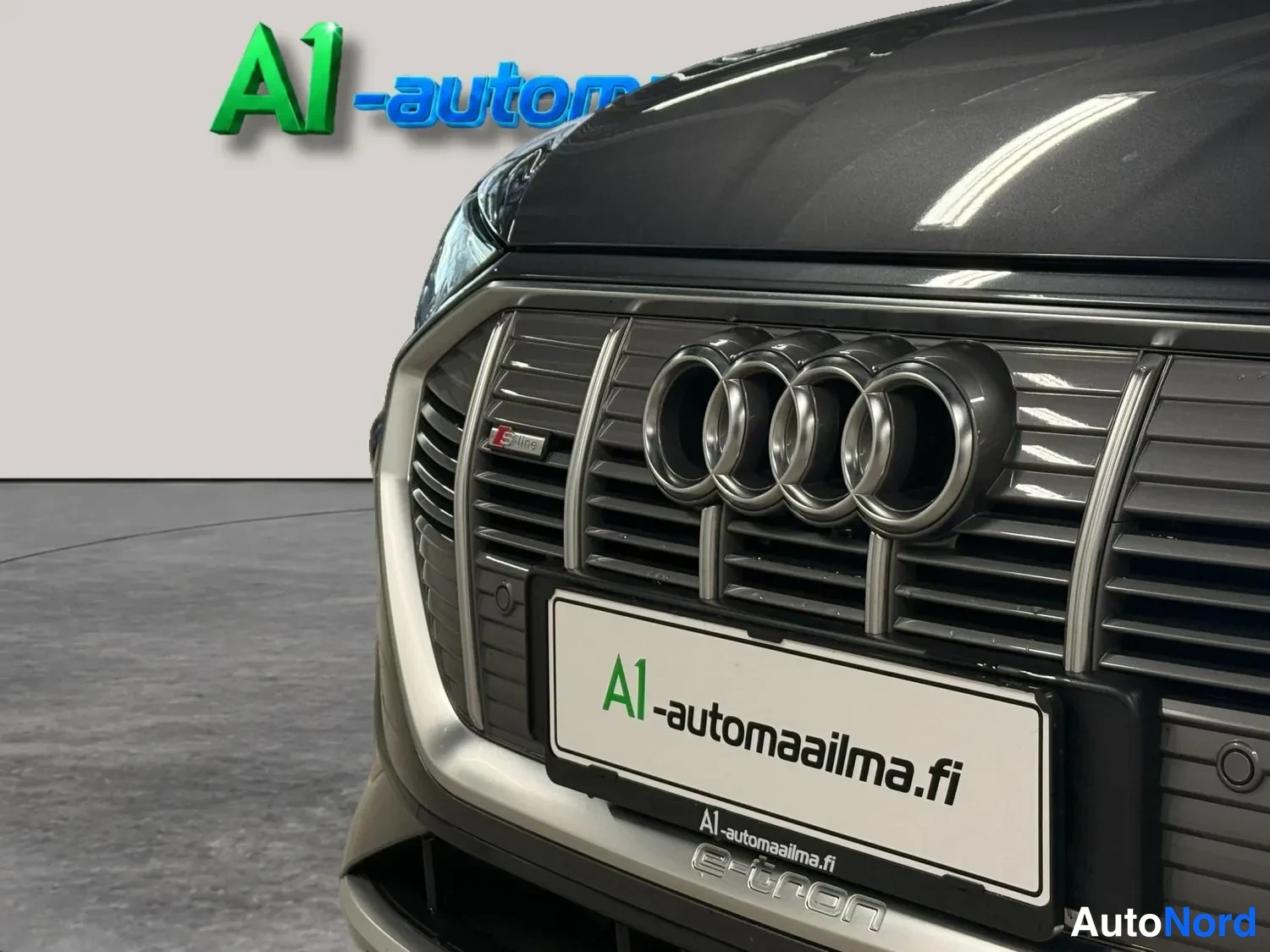 Edestä: Audi e-tronin etusäleikön lähikuva neljällä renkailla-merkillä ja A1-automaailman tunnuskilvella