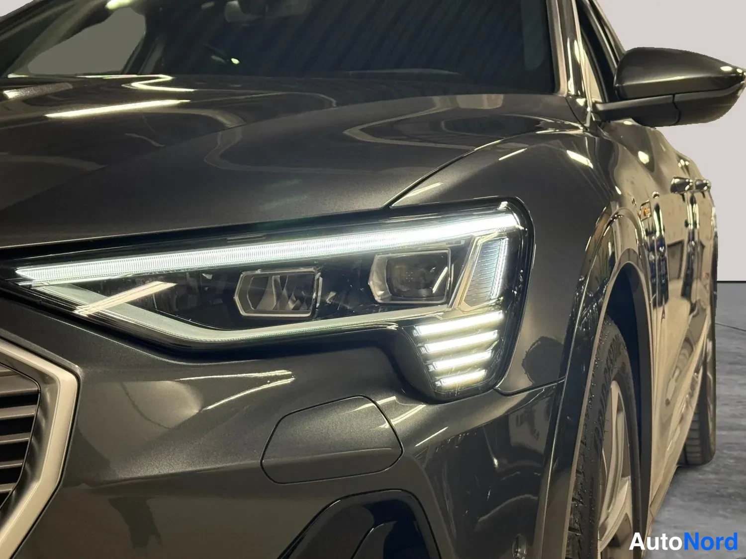 Etuviisto, nokka vasemmalle: Audi e-tronin LED-etalijan lähikuva harmaassa autotallissa