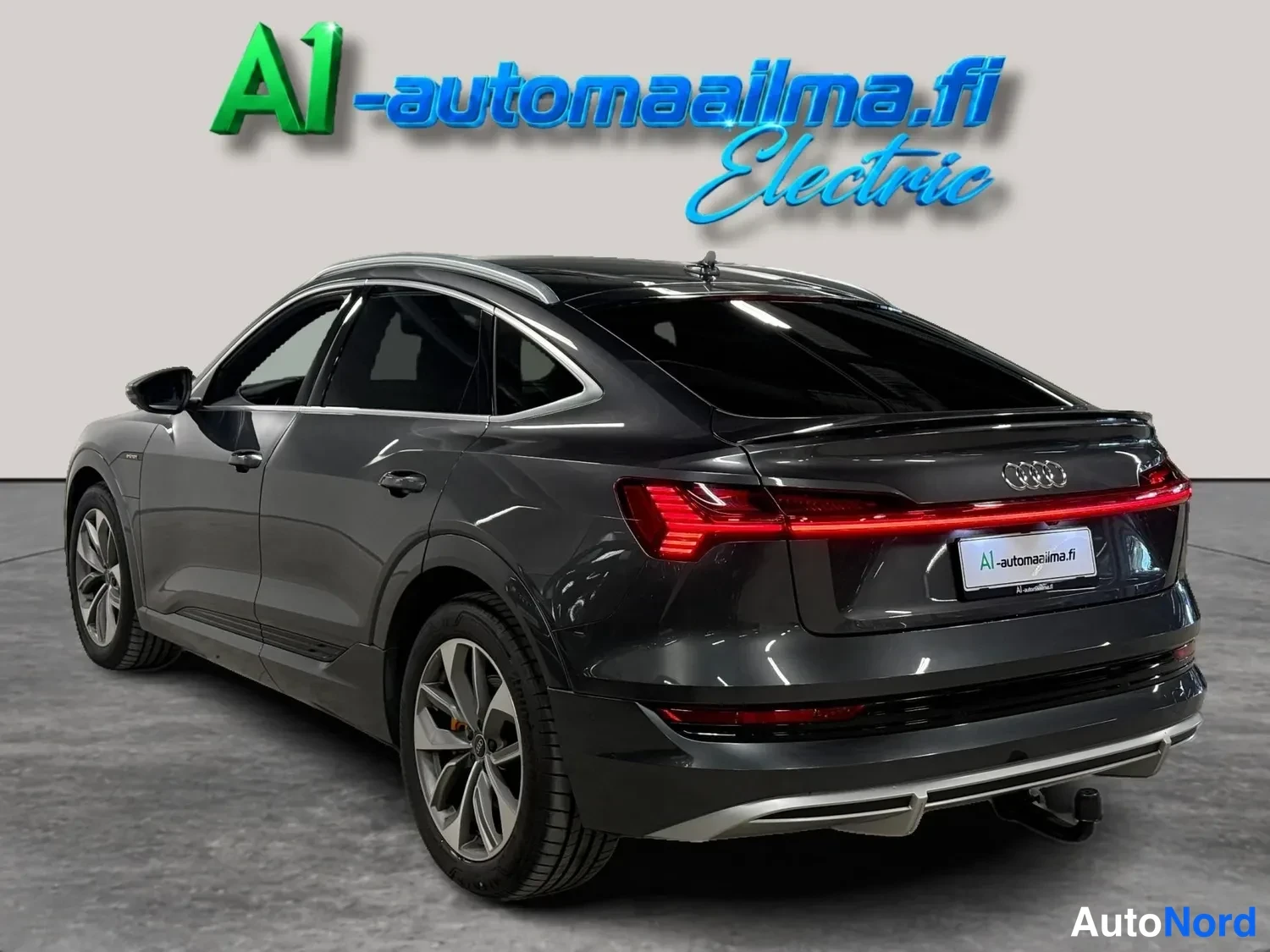 Takaviisto: Taka-3/4-näkymä tummanharmaasta Audi Sportback -mallista, jossa näkyvät takavalot, pakoputkien sijaan koristeellinen takapuskuri, kattoteline ja rekenteen vetok