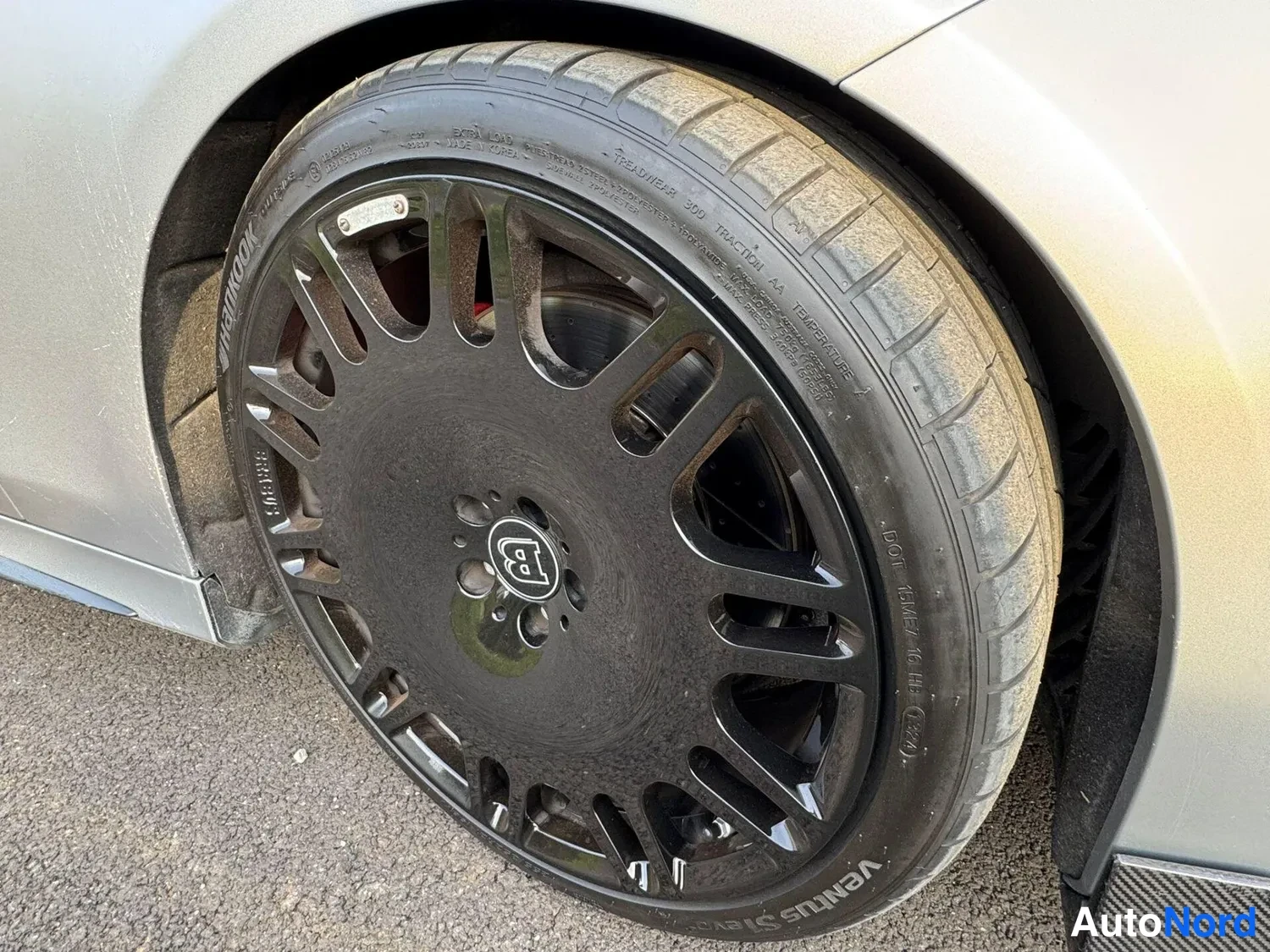 Yksityiskohta: Musta moniosainen vanteen pinnallinen rengas Hankook Ventus S1 evo3, Brabus-tunnuksella napissa; hopea karossaaria reunustaa kuva.