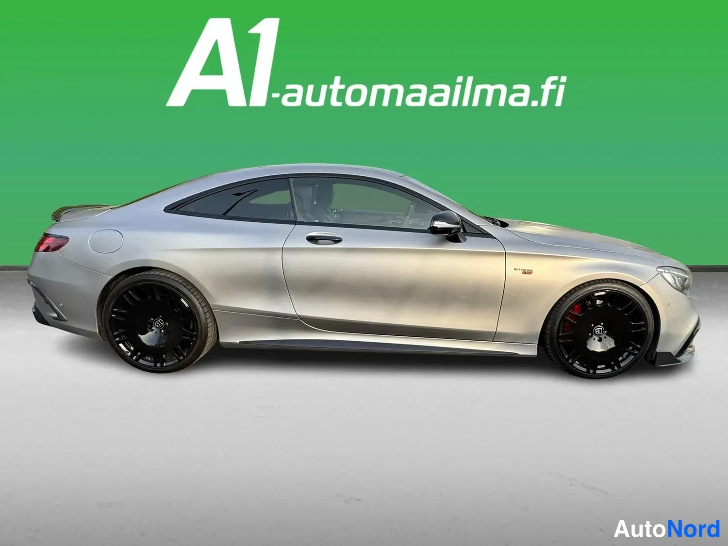Takaviisto: Hopeanharmaa coupé sivusta-takaviistosta, mustat kevytmetallivanteet ja punaiset jarrusatulat näkyvät.