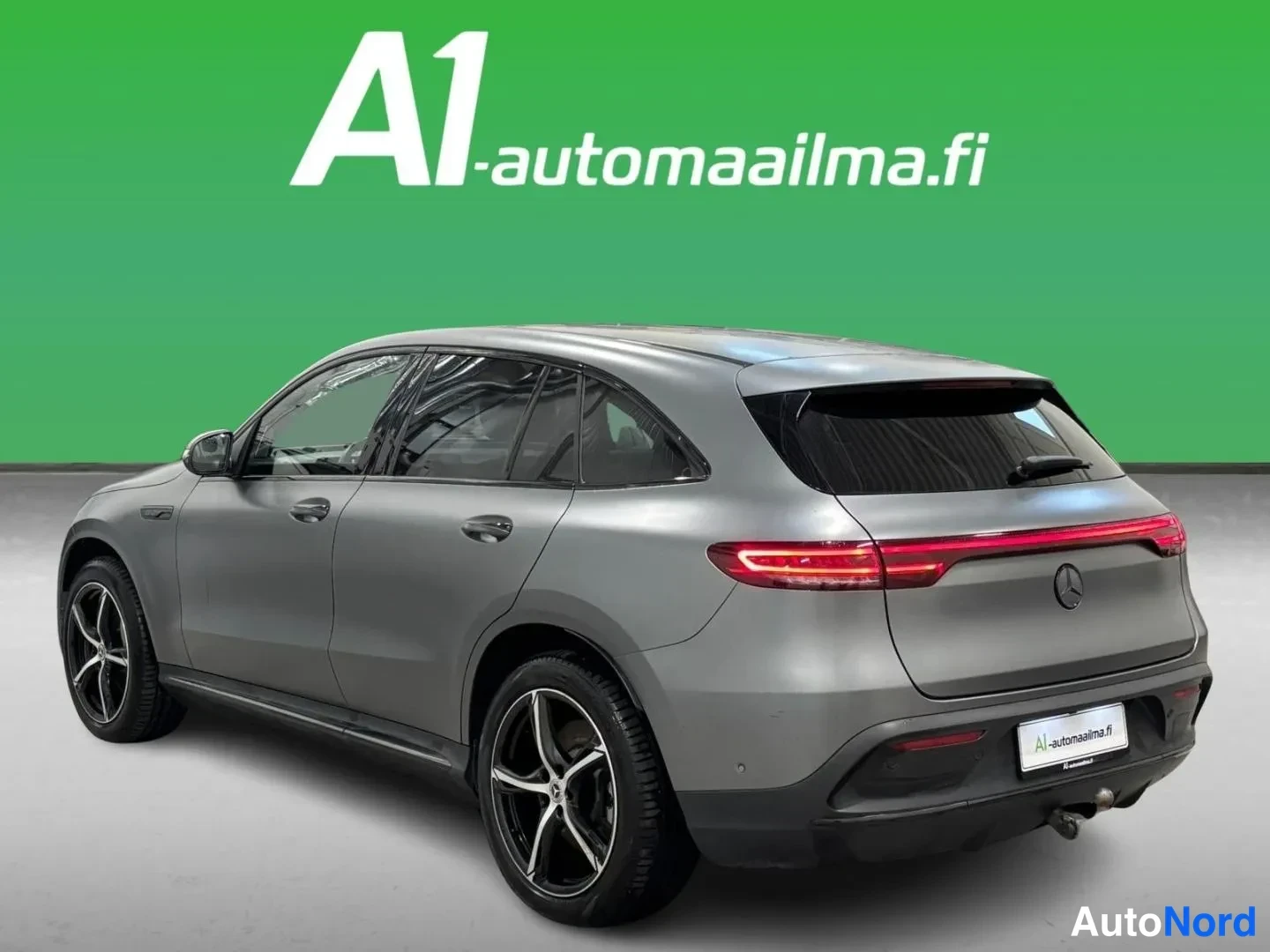 Takaviisto: Hopeanharmaan Mercedes-Benz EQC -maasturin takakulma, punainen takavalotanko ja Mercedes-tähti takaluukussa näkyvissä.
