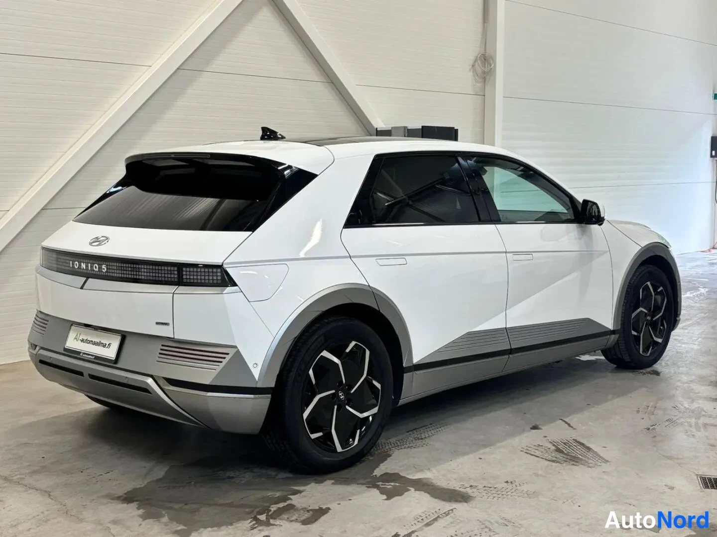 Takaviisto: Valkoisen Hyundai Ioniq 5:n takaosa ja sivuprofiili takavasemmalta kuvattuna, IONIQ 5 -teksti takavalossa.