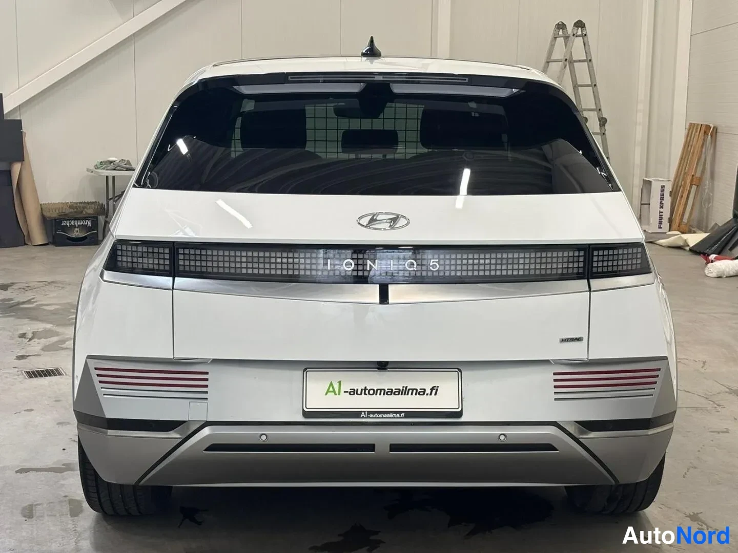 Takaa: Valkoisen Hyundai Ioniq 5:n suora takaosan näkymä, IONIQ 5 -teksti valossa ja A1-automaaailma.fi -kyltti rekisterinpaikalla.
