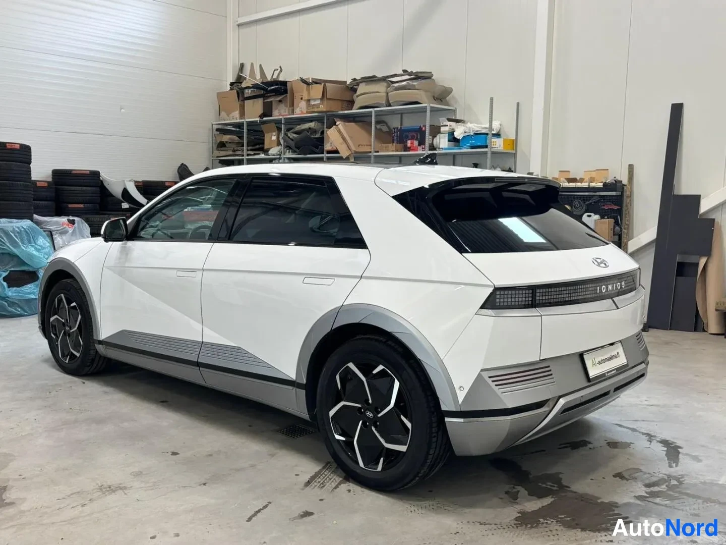 Takaviisto: Hyundai Ioniq 5:n takakolmannesvalokuva: valkoinen korirakenne, takamoottoritie ja takavalot kuvattuna huoltotilassa.