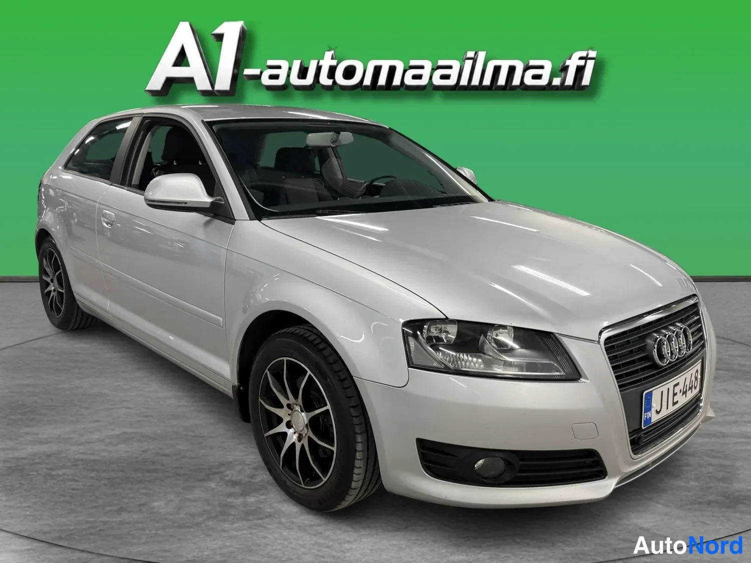 Etuviisto, nokka oikealle: Hopeanvärinen kolmiovinen Audi A3 -henkilöauto esitettynä studio-maisemassa, kuvakulma edestä oikealta.