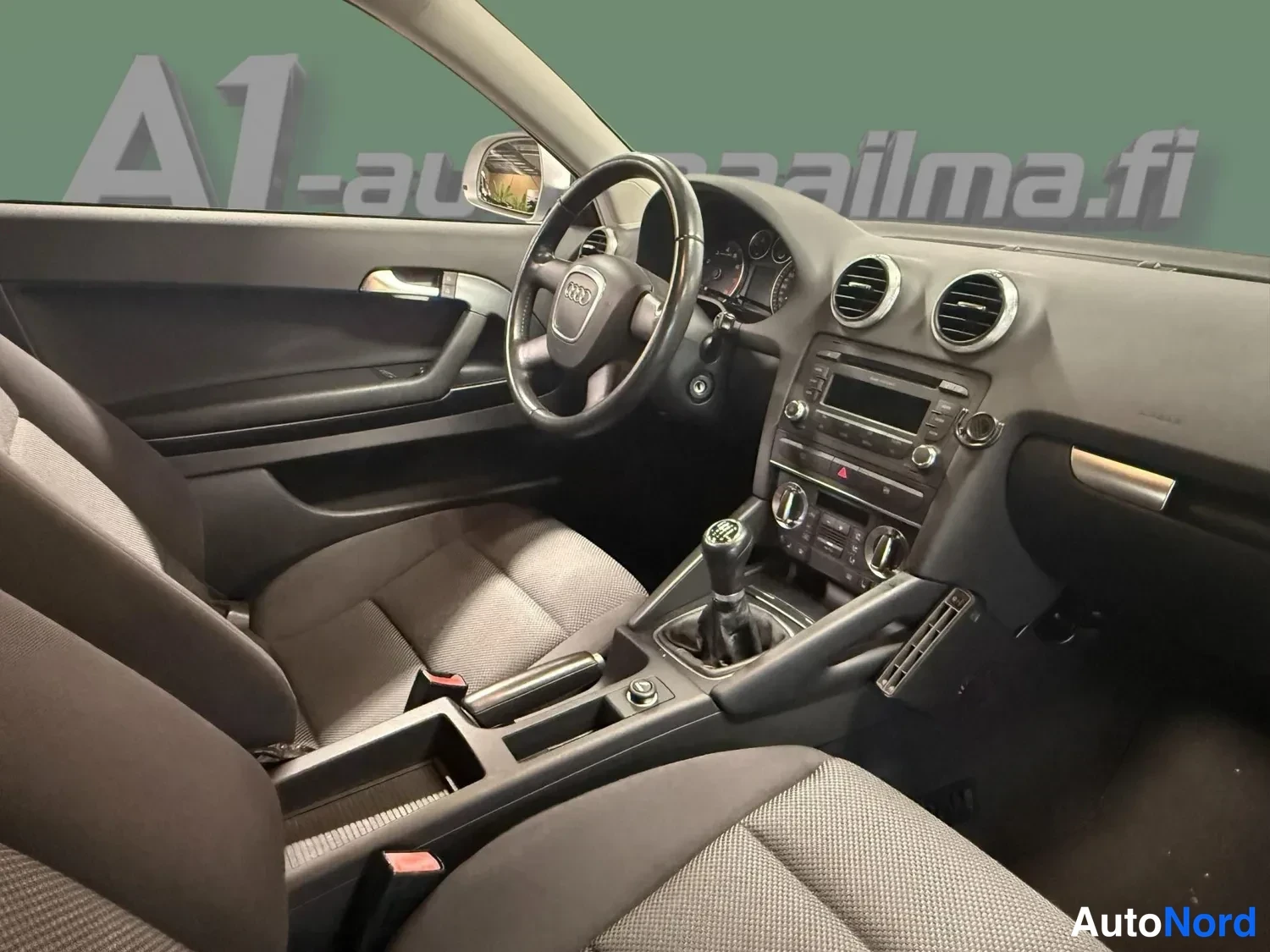 Muu: Ohjaamo näkyvissä: kaksipaikkainen etuistuinosa, manuaalivaihteen keila, Audi-ohjauspyörä ja kojetaulu.