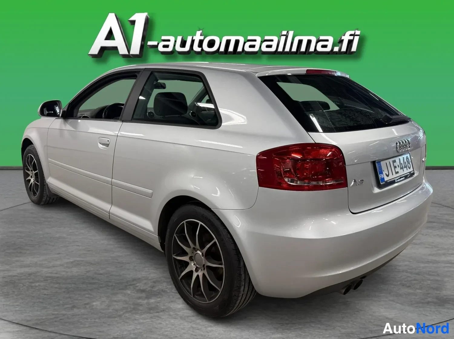 Takaviisto: Audi A3 -mallin hopeanvärinen kori näkyy takaa sivulta; takavalo, nellin takapää ja vasemman sivun ovet sekä hybridivanteen rengas ovat näkyvissä.
