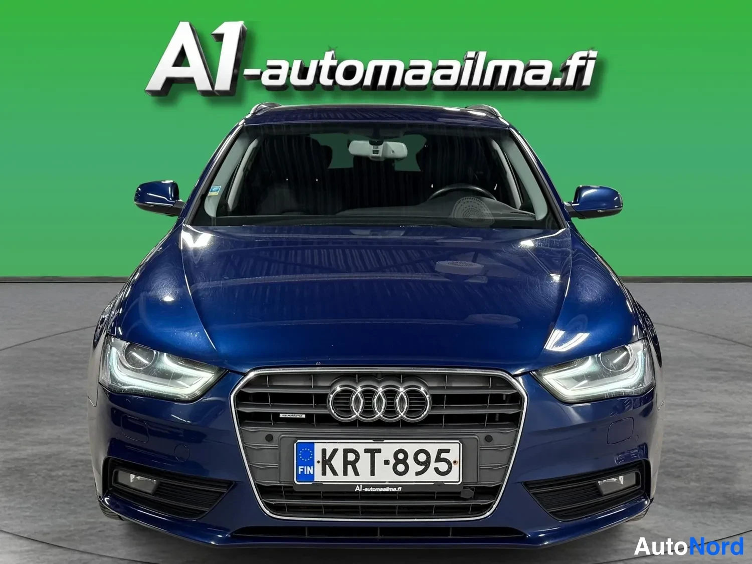 Edestä: Audi A4 Avant edestäpäin, tummansininen kori ja rekisteritunnus.
