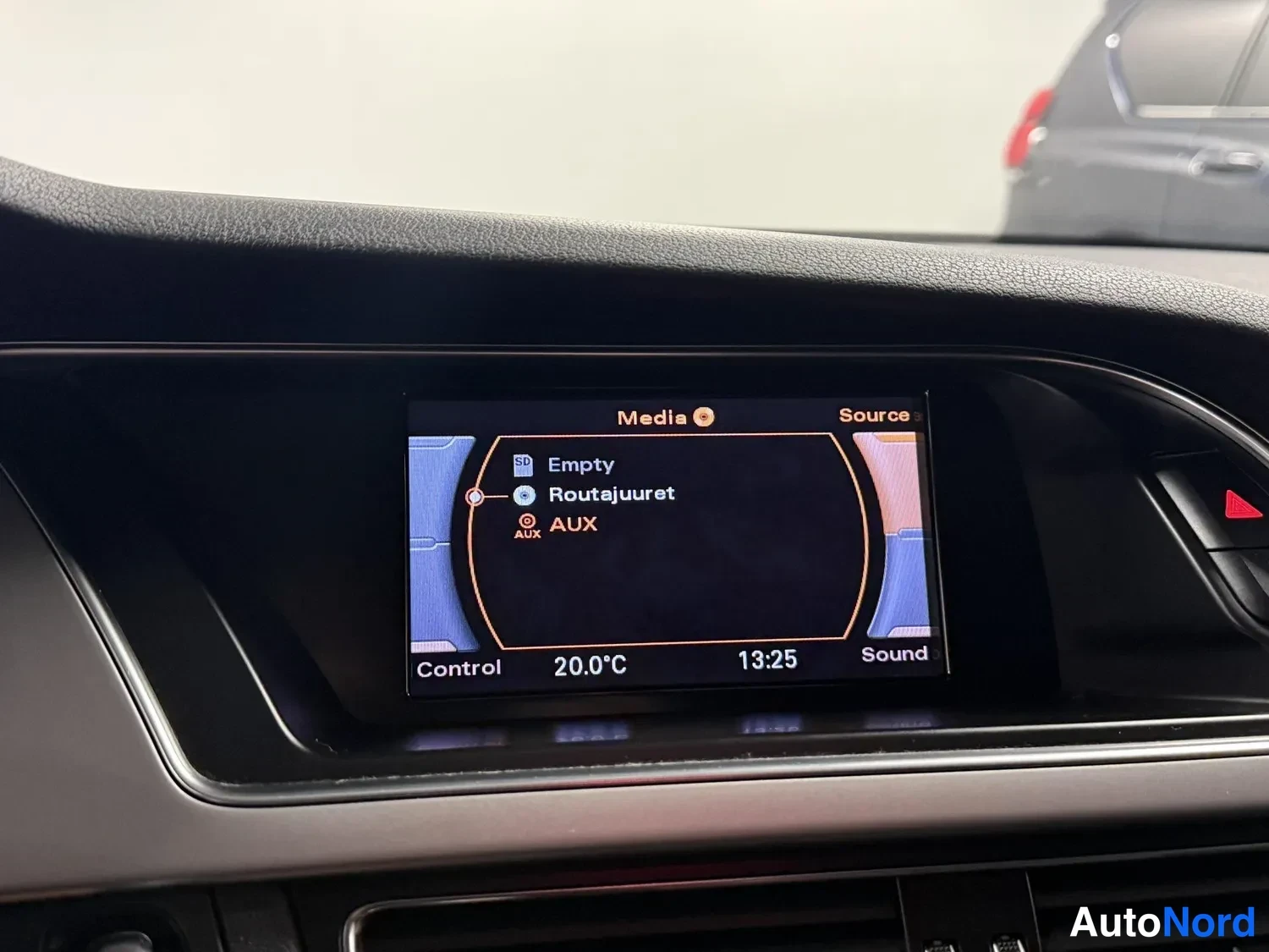 Yksityiskohta: Auton infotainment-näyttö Media-valikossa lähteillä SD-kortti (Empty), Routajuuret ja AUX; alareunassa Control, 20.0°C, 13:25 ja Sound.
