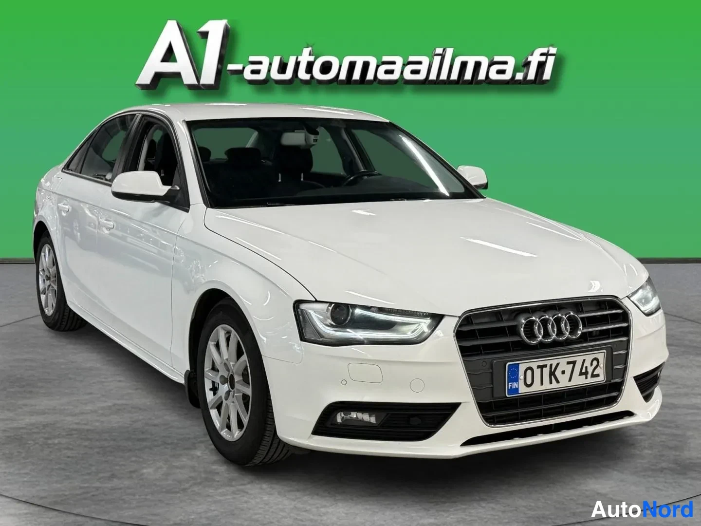 Etuviisto, nokka oikealle: Audi A4 Business 2,0 TDI 2012, etukulmakuva: valkoinen sedan, etupuskuri, konepelti ja grilli kuvan oikealla, vasen sivu näkyvissä.
