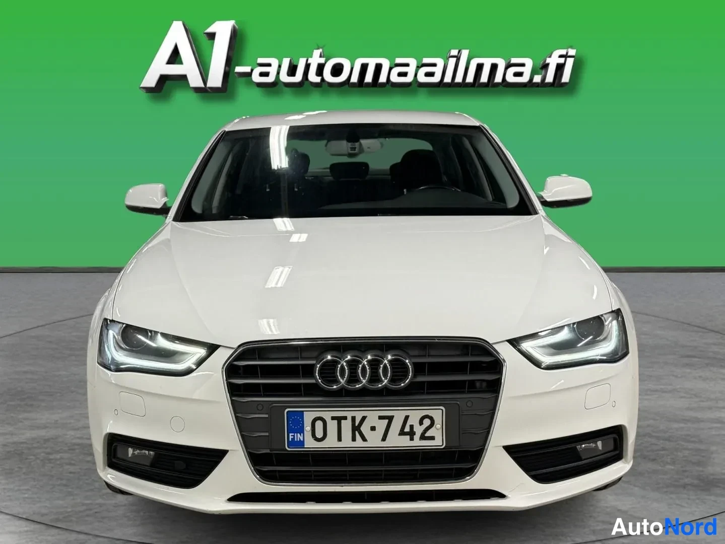 Edestä: Audi A4 Business 2,0 TDI 2012, suora etukuva: valkoinen sedan, Audi-merkki kiiltävän mustassa etusäleikössä, rekisterikilpi.