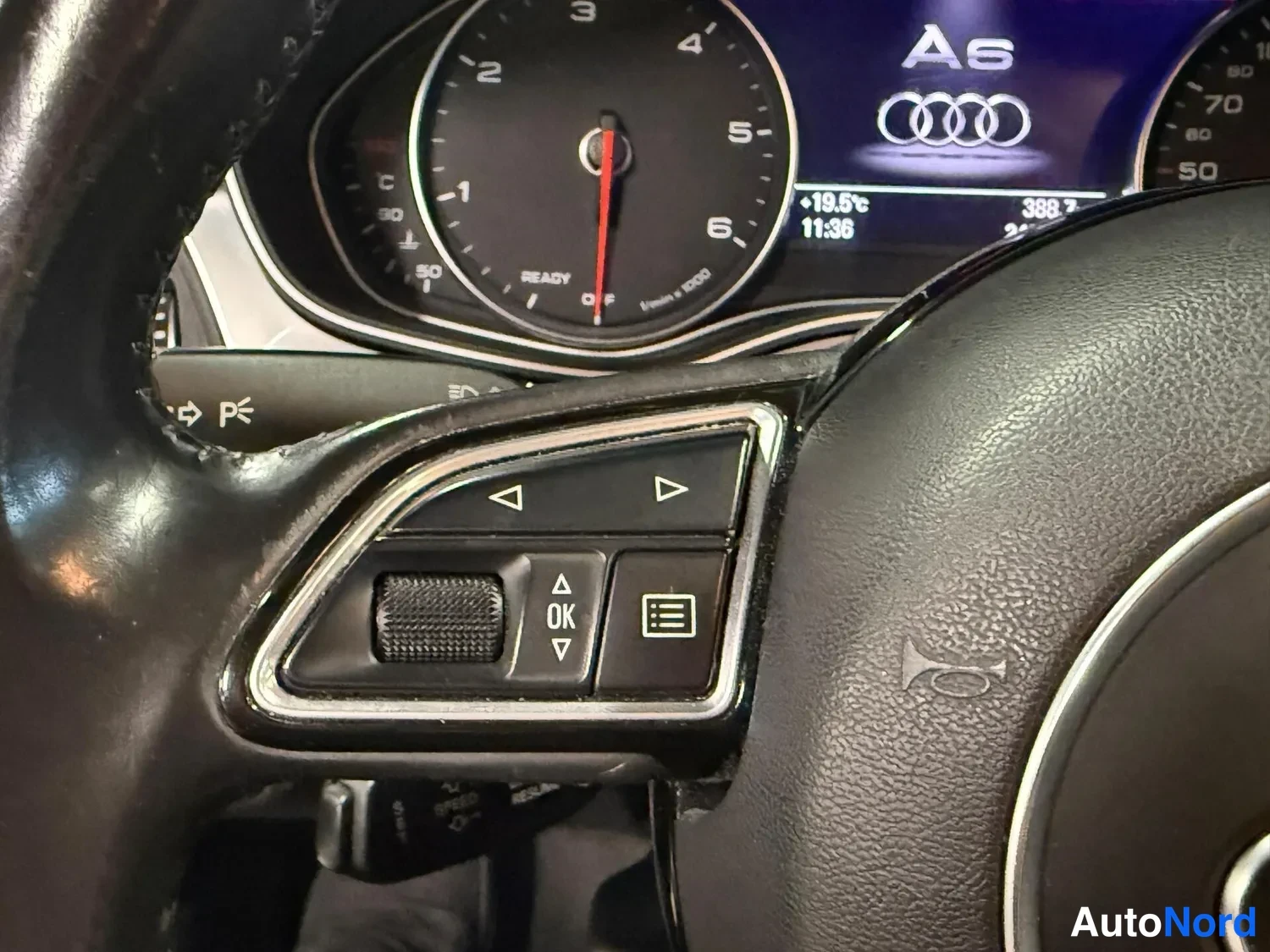 Muu: Kojeiston läheiskuva: kierroslukumittari, näytöllä Audi-neljä renasta ja teksti "A6", lämpötila +19,5°C, kellonaika 11:36 sekä laskuri 388.7, ja rattaan valikko