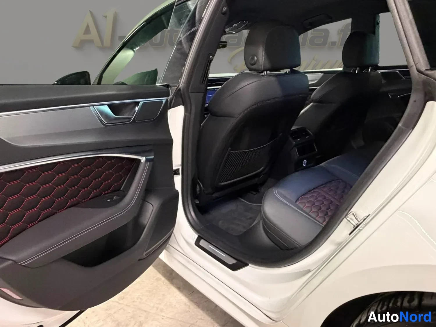 Sivulta: Logoteksti 'Audi Centrum' ja sen alla pienempi teksti, ei täysin luettavissa. Taustalla auton etupyörä ja etupuskuri.