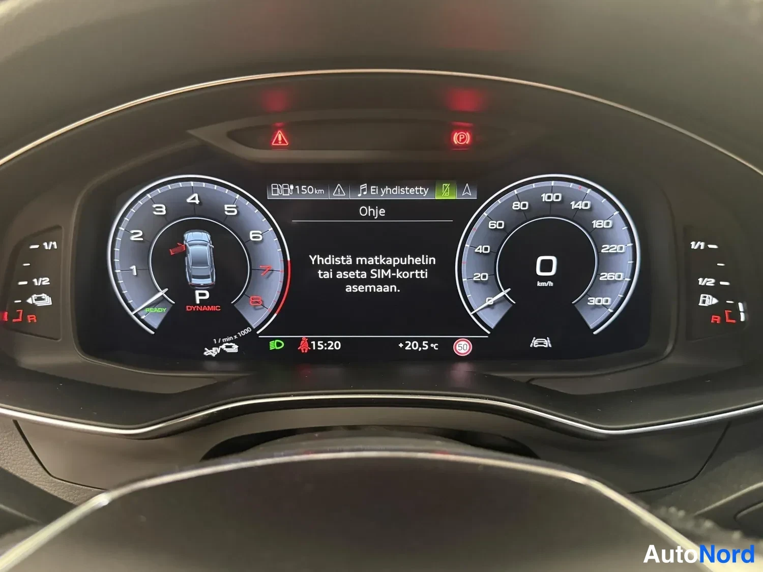Muu: Audi A7:n digitaalinen mittaristo ajoneuvo seisaallaan: vaihde P, nopeus 0 km/h, näytöllä ohje 'Yhdistä matkapuhelin tai aseta SIM-kortti asemaan.'