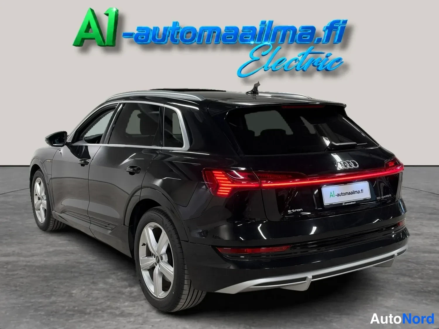 Takaviisto: Mustan Audi e-tronin takanäkymä hieman vasemmalta, valot ja hopeavanteet näkyvät.