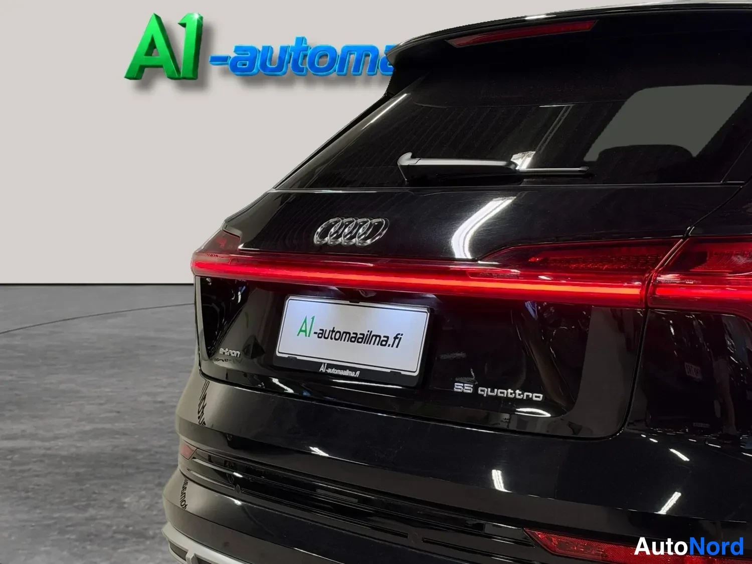 Takaa: Lähikuva mustan Audi e-tronin takaosasta, jossa näkyy e-tron-merkintä ja A1-automaailma.fi -teippaus.