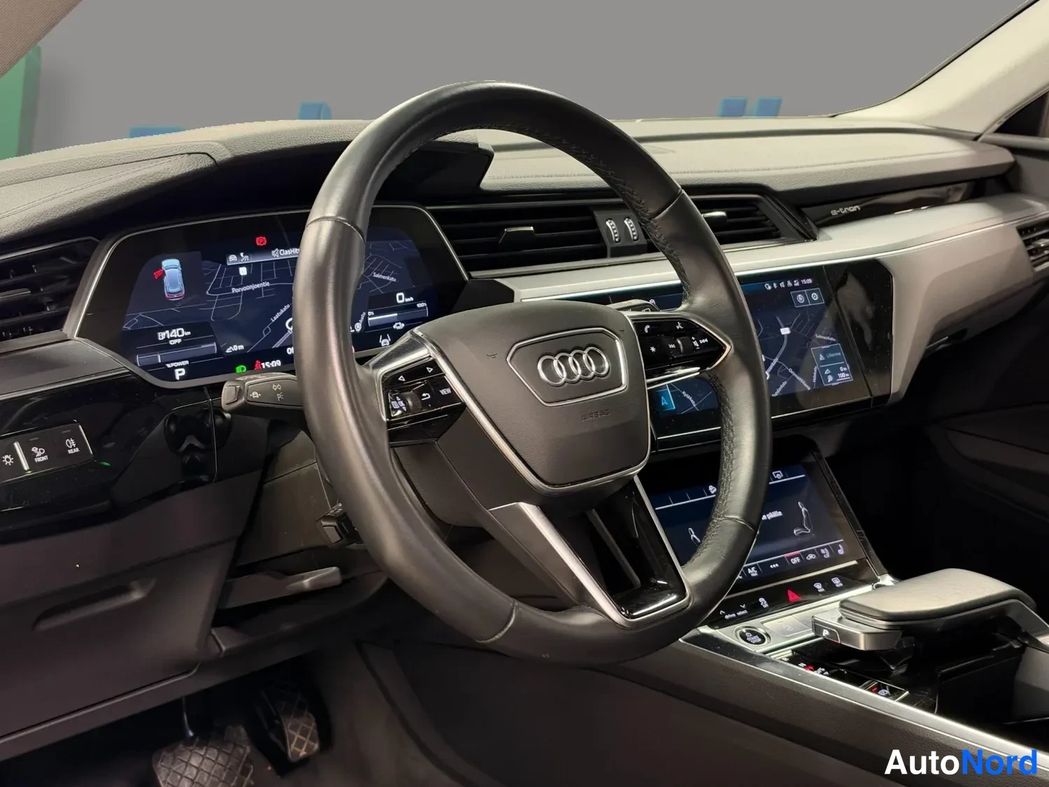 Etuviisto: Audi-ohjauspyörä, digitaalinen mittaristo ja kosketusnäytöt, vaihteenvalitsin P-asennossa.