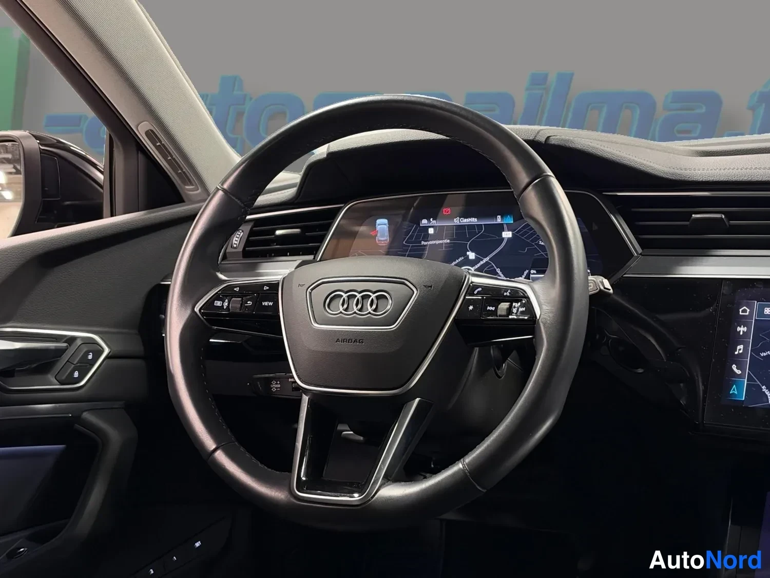Muu: Ohjauspyörä ja osa kojelaudasta, Audi-merkki ohjauspyörässä ja digitaalinen mittariston kartta.