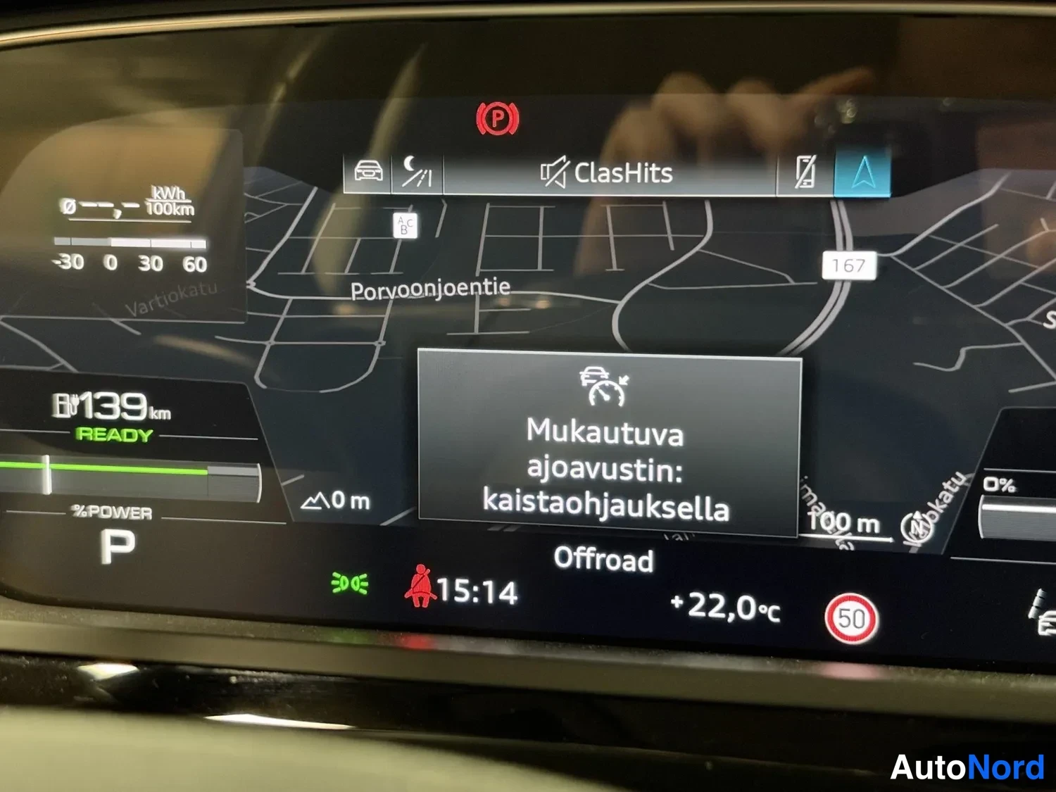 Yksityiskohta: Kojelaudan näyttö, jossa viesti 'Mukautuva ajoavustin: kaistaohjauksella', jäänyt 139 km ja karttanäkymä.