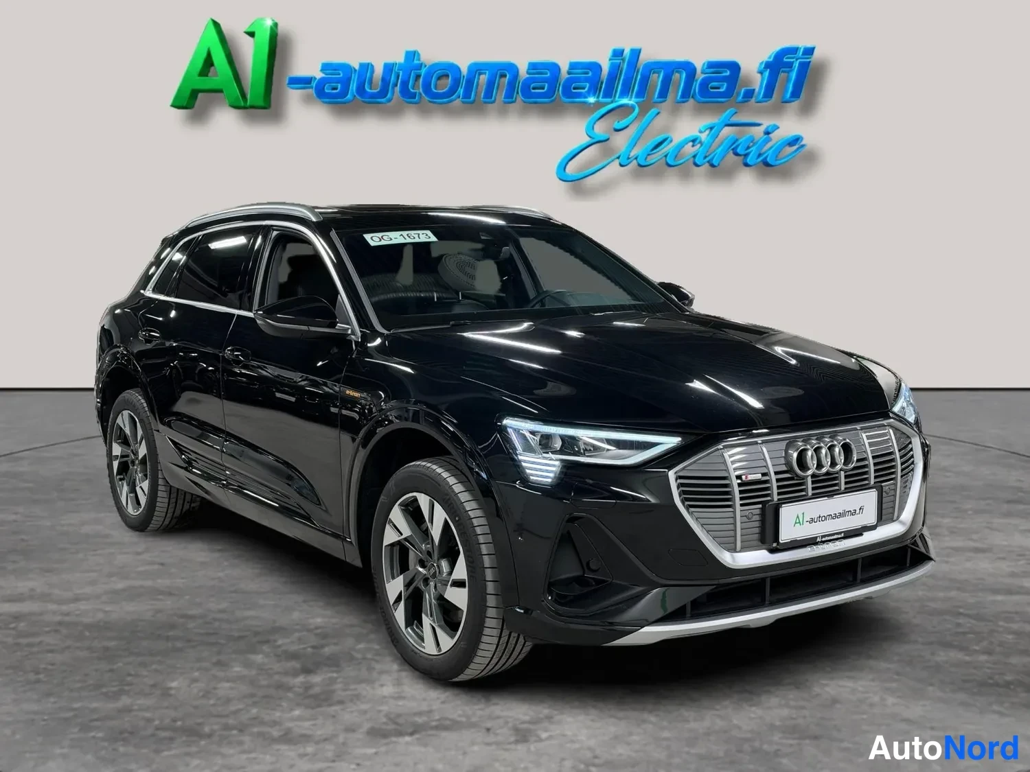 Etuviisto, nokka oikealle: Musta Audi e-tron -maasturista otettu etu-neljänneskuva, jossa näkyvät etusäleikkö, X-malliset LED-ajovalot ja vasemman puolen ovet kulmikkailla neljän o