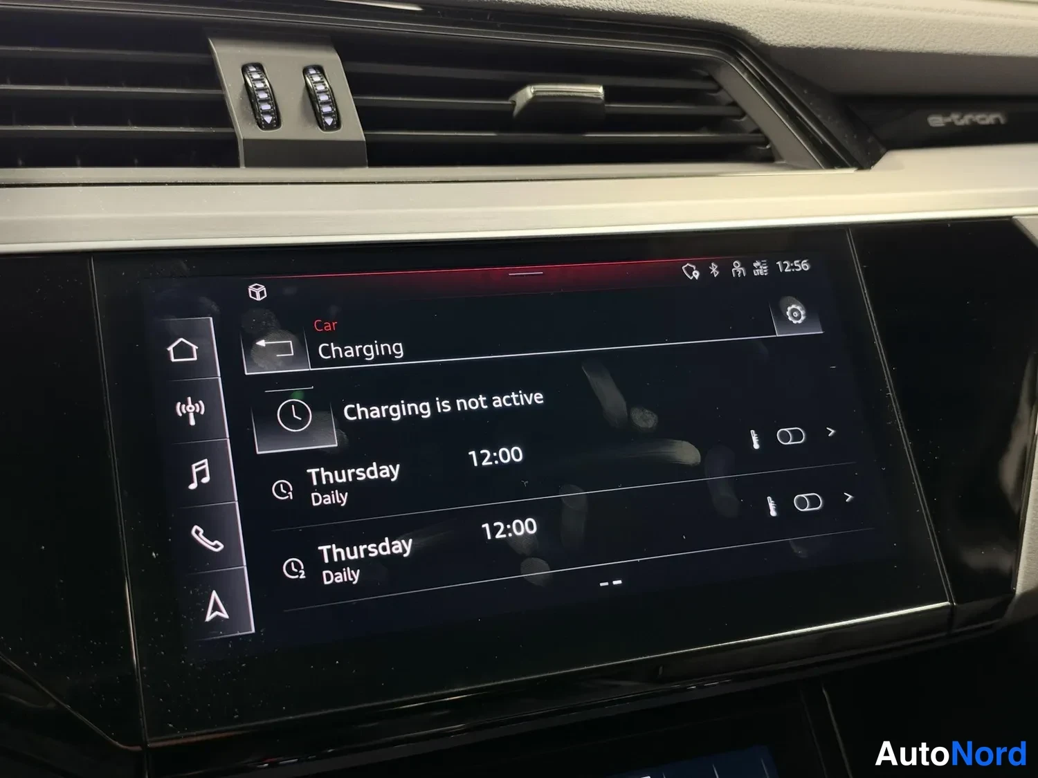 Yksityiskohta: Kojelaudan infotainment-näyttö latausvalikossa; teksti 'Charging is not active' ja kaksi torstaisin klo 12:00 toistuvaa aikataulua.