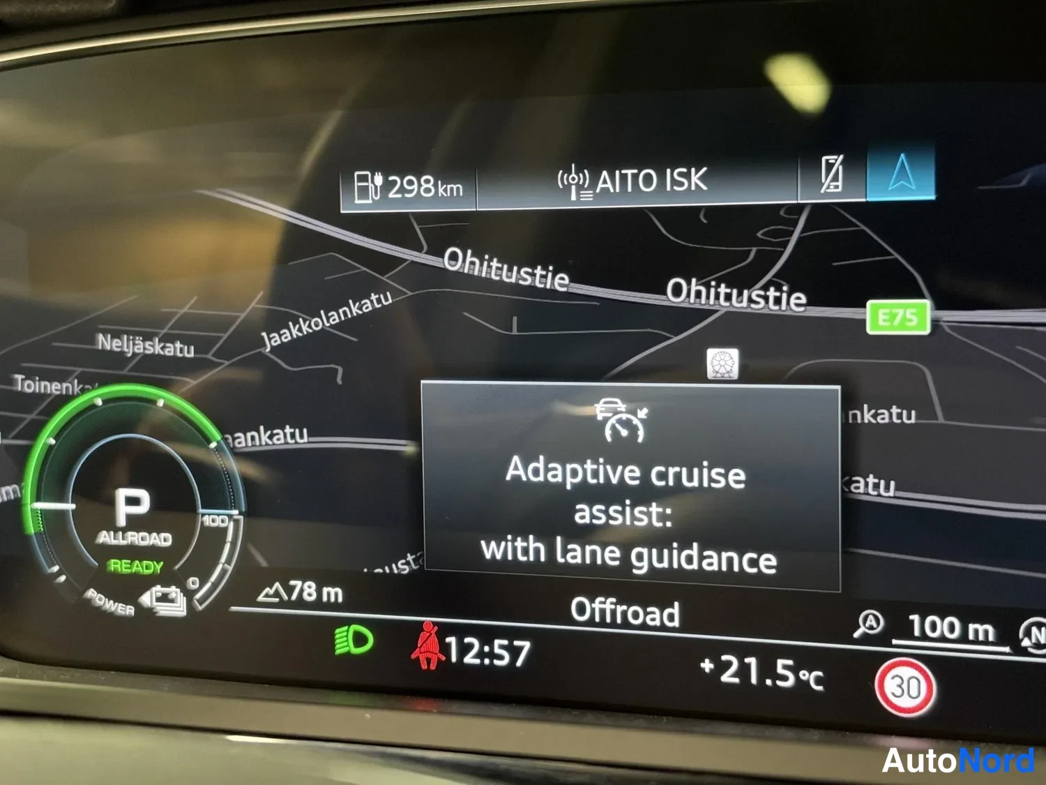 Yksityiskohta: Kuljettajan näytön kartta ja tietopalkki: laskettu toimintamatka 298 km, vaihde P (READY), 'Adaptive cruise assist: with lane guidance' -teksti, lämpötila +21,5