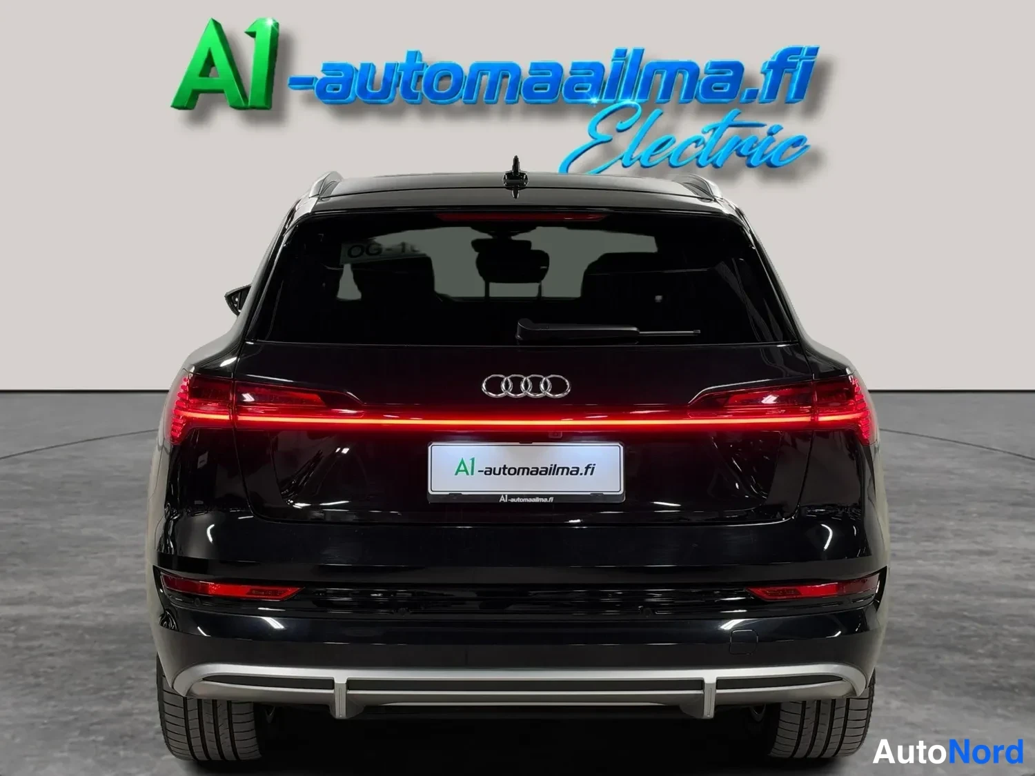 Takaa: Mustan Audi e-tronin takanäkymä: punainen valojohto kiinni rekisterikilvessä lukee A1-automaailma.fi.