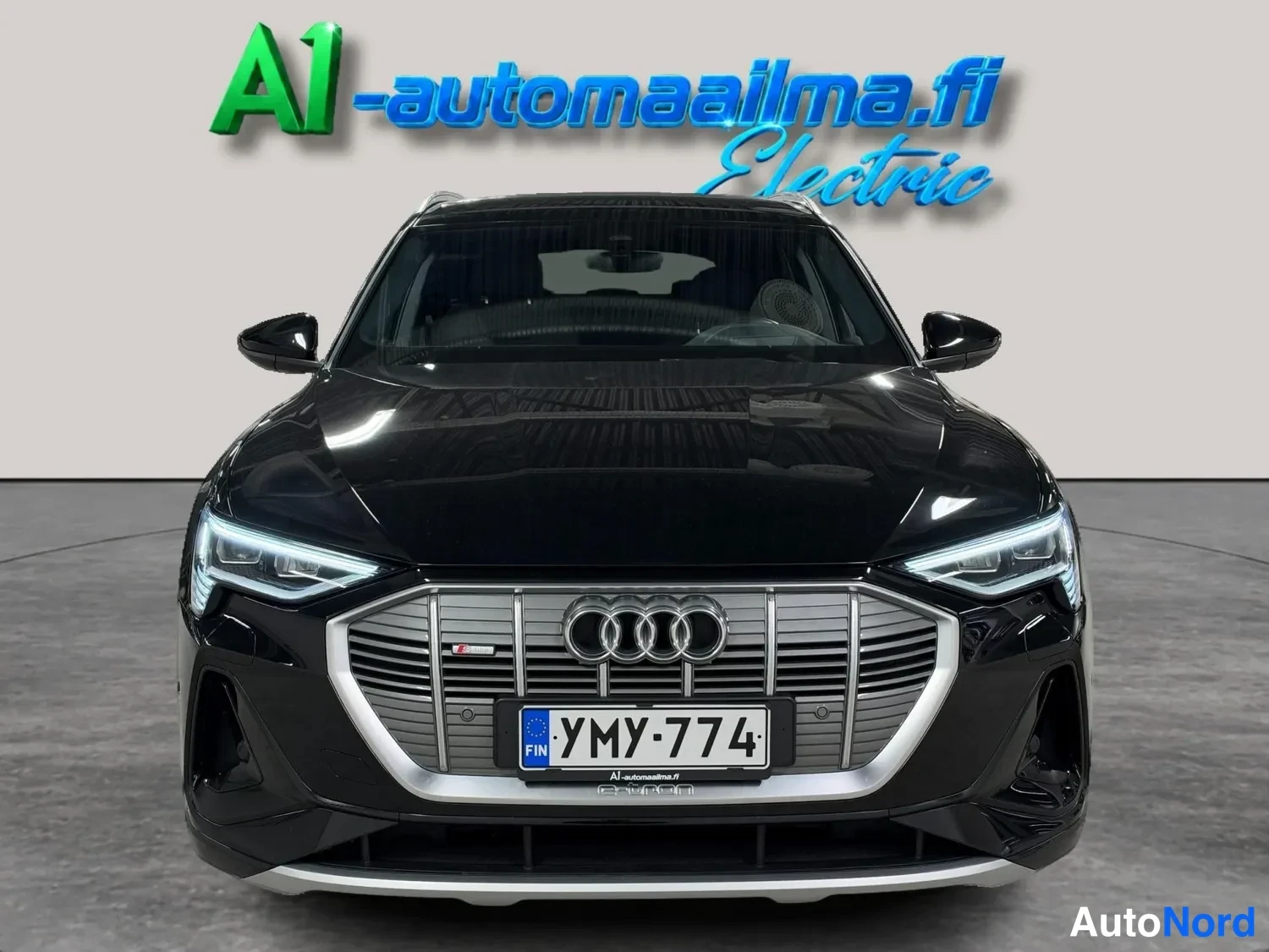 Edestä: Audi e-tronin etukuva suoraan edestä, musta kori, nokkamallinen etusäleikö ja rekisteritunnus.