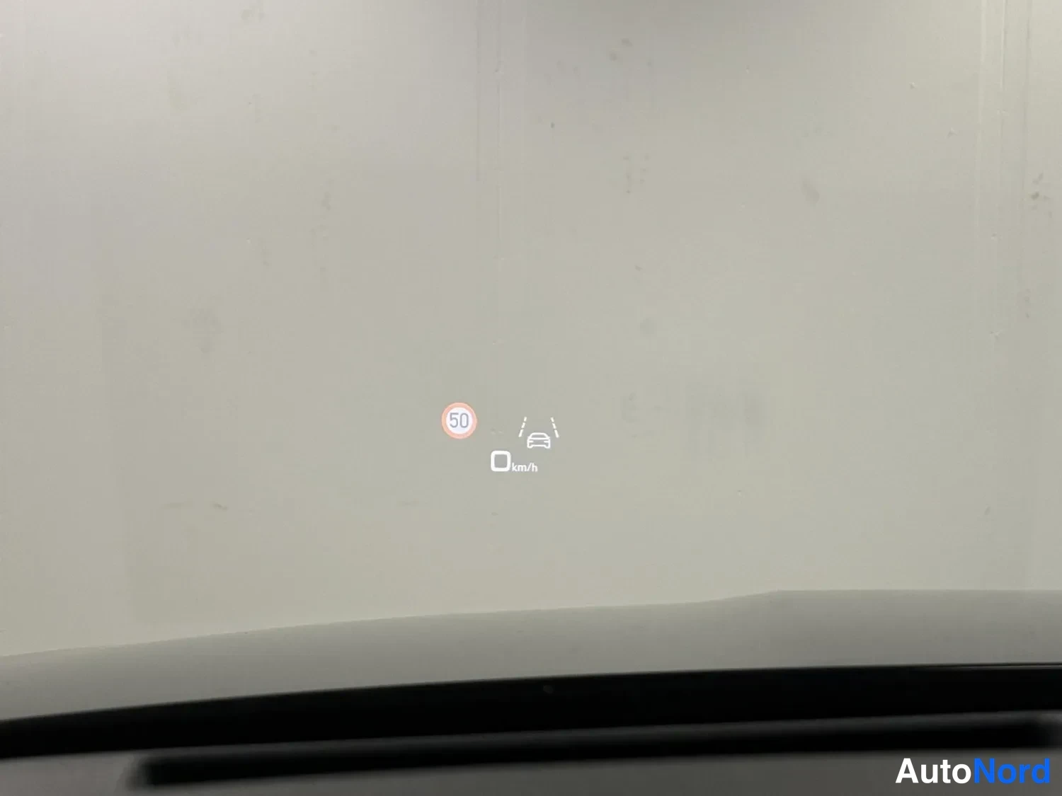 Muu: Tuulilasin ajonäytön (head-up display) kuva: 50 km/h nopeusrajoitusmerkki ja kaistapitäjän symboli näkyvät heikosti.