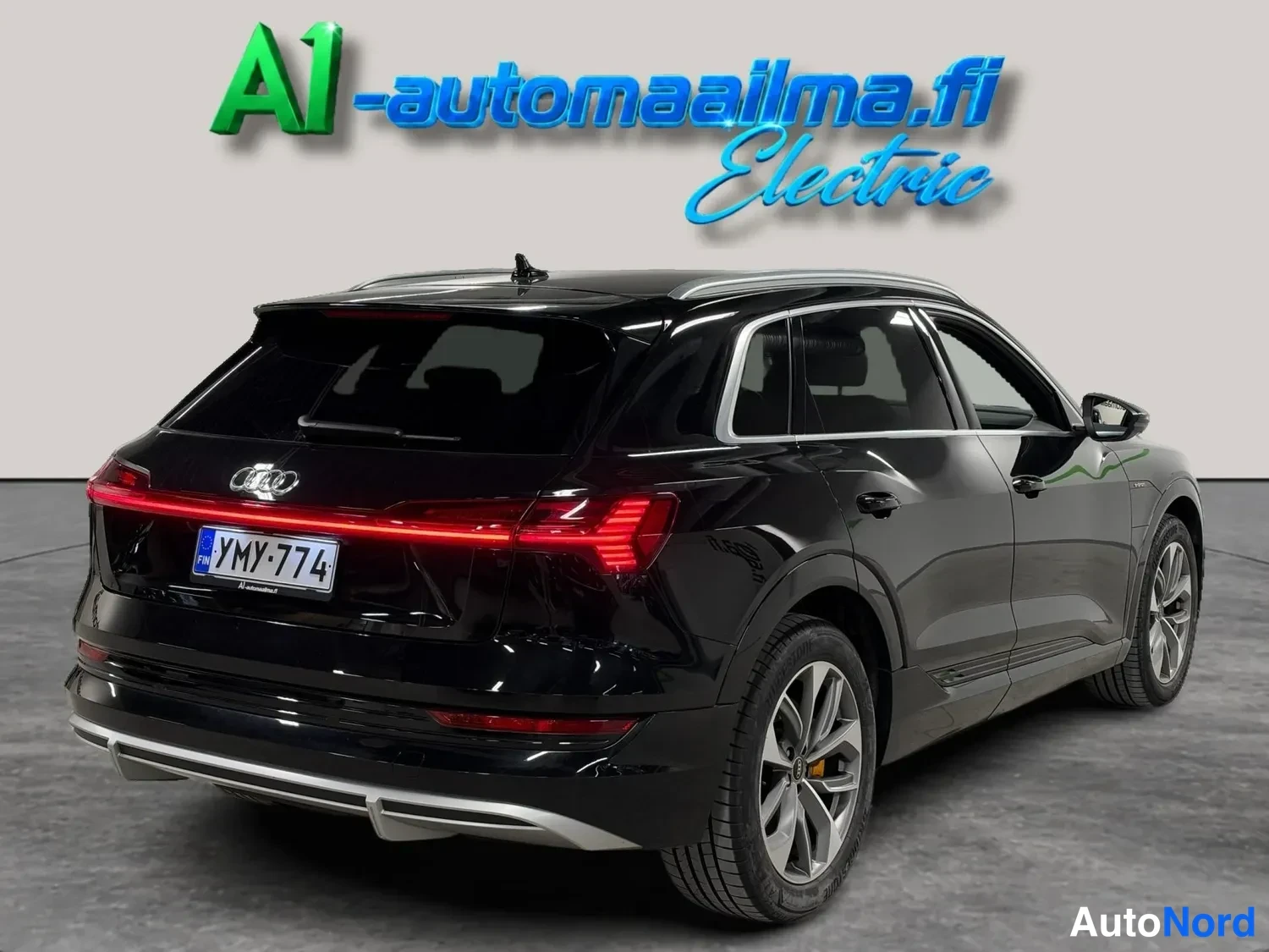 Takaviisto: Audi e-tronin takanurkkakuva, musta kori, punainen takavalotunnus ja rekisteritunnus.