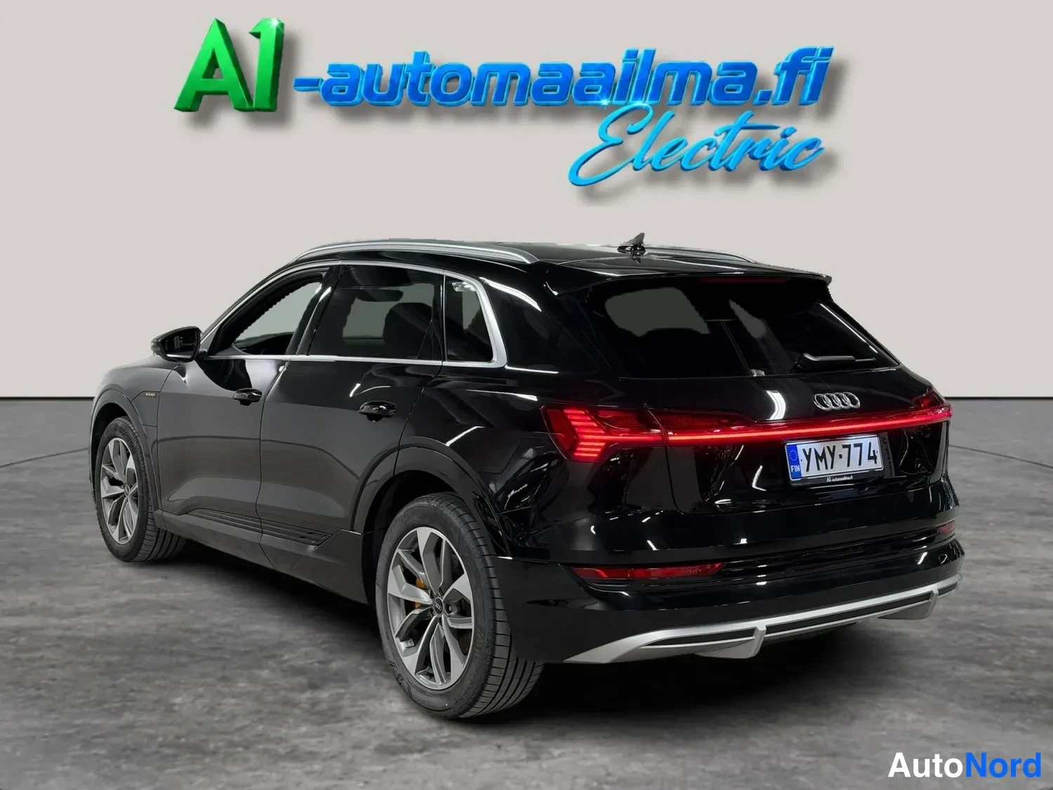 Takaviisto: Mustan Audi e-tronin takaosa ja vasen sivuprofiili, kk-merkkivalot ja rekisterikilpi näkyvissä.