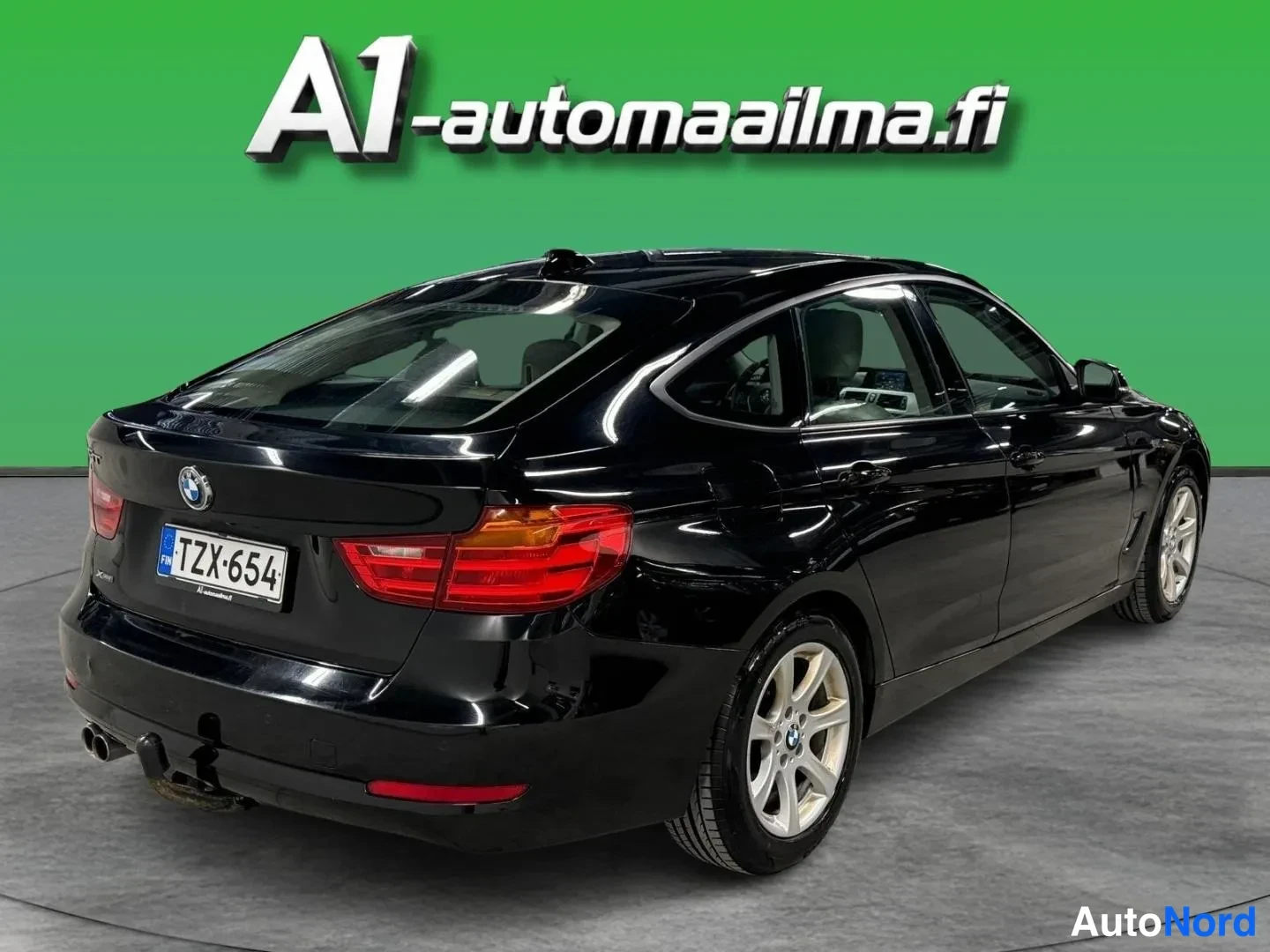 Takaviisto: Mustan BMW:n takakulmanäyttö: takapovi, panoraamimainen takaikkuna, -rekisterikilpi ja vetokoukku näkyvät, särmäkiekko oikeassa etualalla.