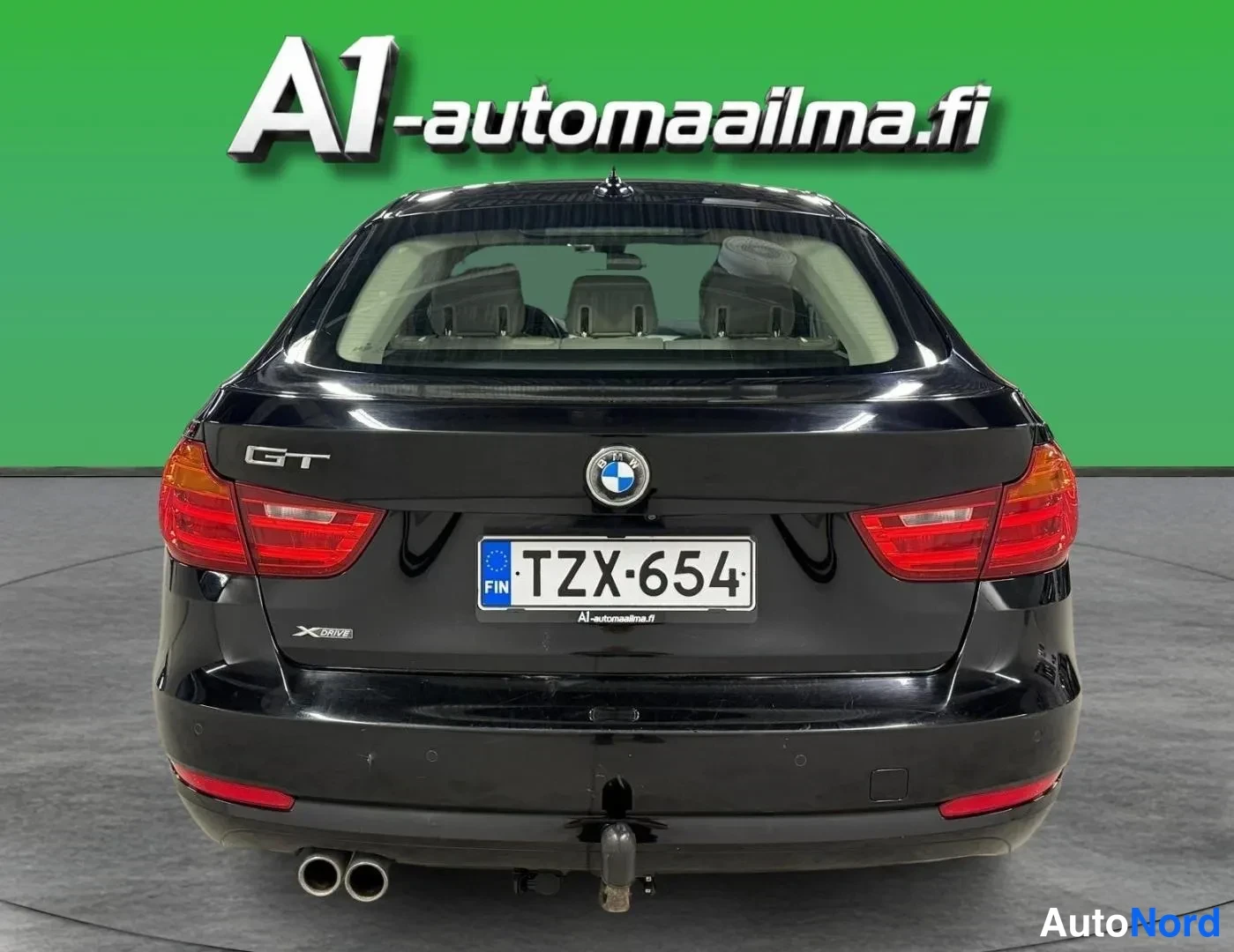 Takaa: Mustan BMW:n takaosa suoraan takaa: GT-merkintä, BMW-merkki, -kilpi, kaksiosainen pakoputki ja vetokoukku.