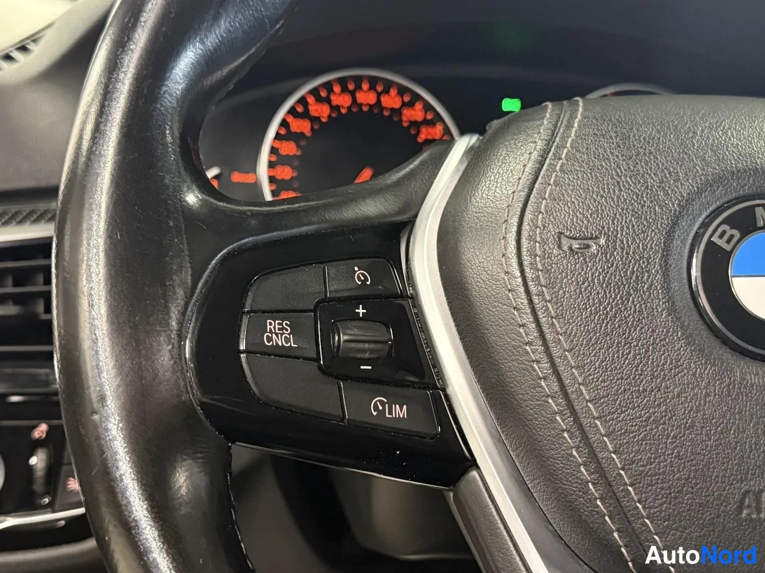 Muu: Ohjauspyörän vasen puhallus: painikkeet 'RES CNCL' ja 'LIM' sekä +/--rulla, BMW-emblem näkyvissä.