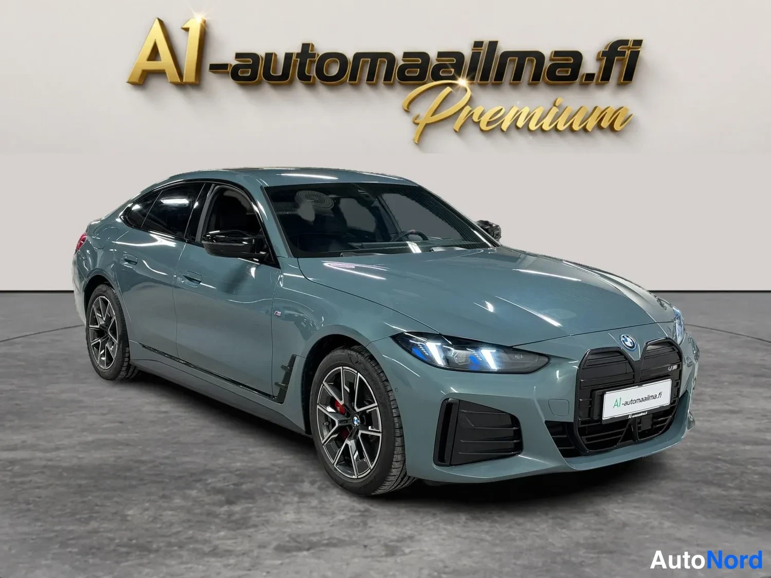 Etuviisto, nokka oikealle: BMW i4 etuviisto oikealta, harmaa viisiovinen coupé, LED-etelovalot ja musta etuspoileri näkyvissä.