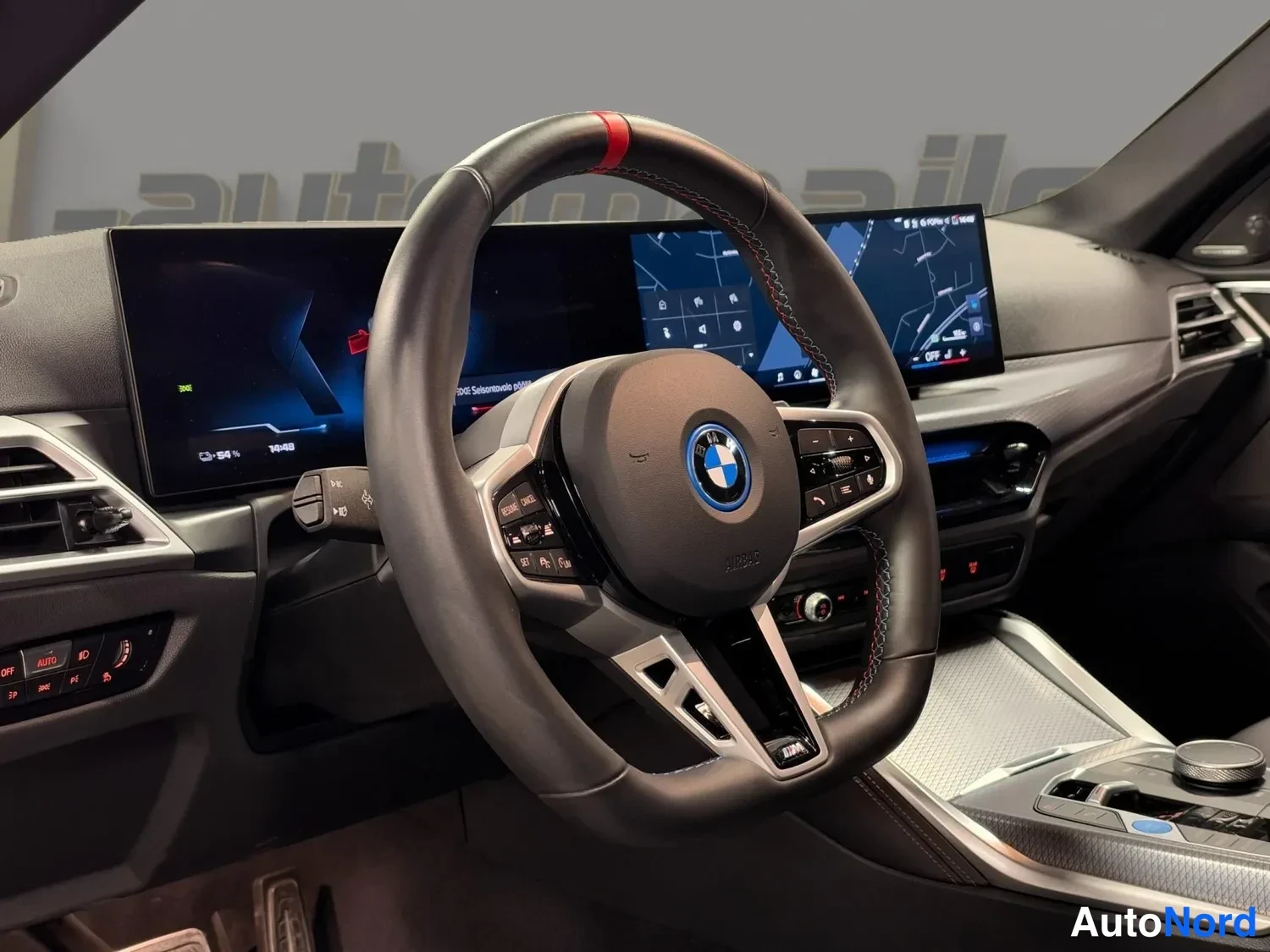 Muu: Ohjauspyörä ja leveä infotainment-näyttö autopilot-karttakuvalla, M-tyylinen ohjauspyörä punaisella huippumerkinnällä.