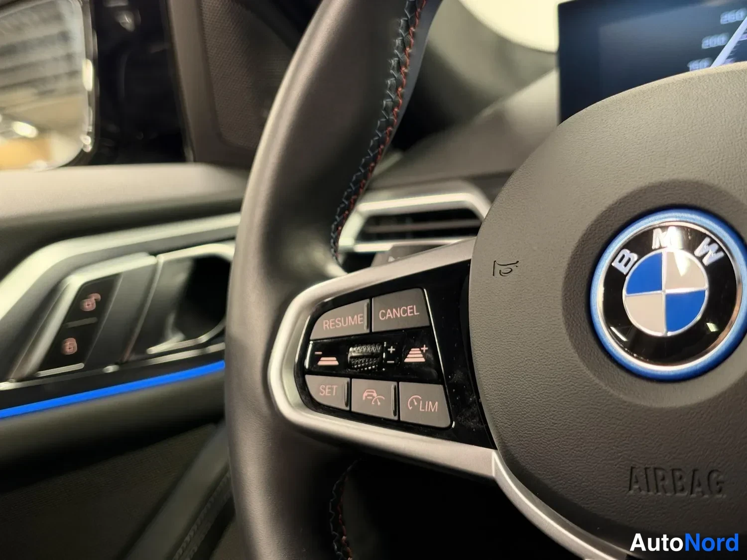 Muu: Sisäkuva BMW:n ohjauspyörästä: vasemmassa ohjainryhmässä näkyvät RESUME-, CANCEL-, SET- ja LIM-painikkeet, keskellä BMW:n pyöreä merkki ja AIRBAG-teksti.