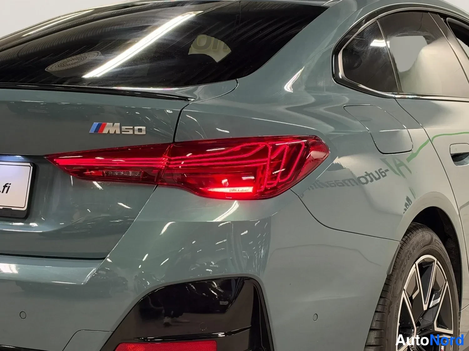 Takaviisto: BMW:n takaosa lähikuvassa: M50-merkki, punainen takavalo ja osa takarenkaasta näkyvät.