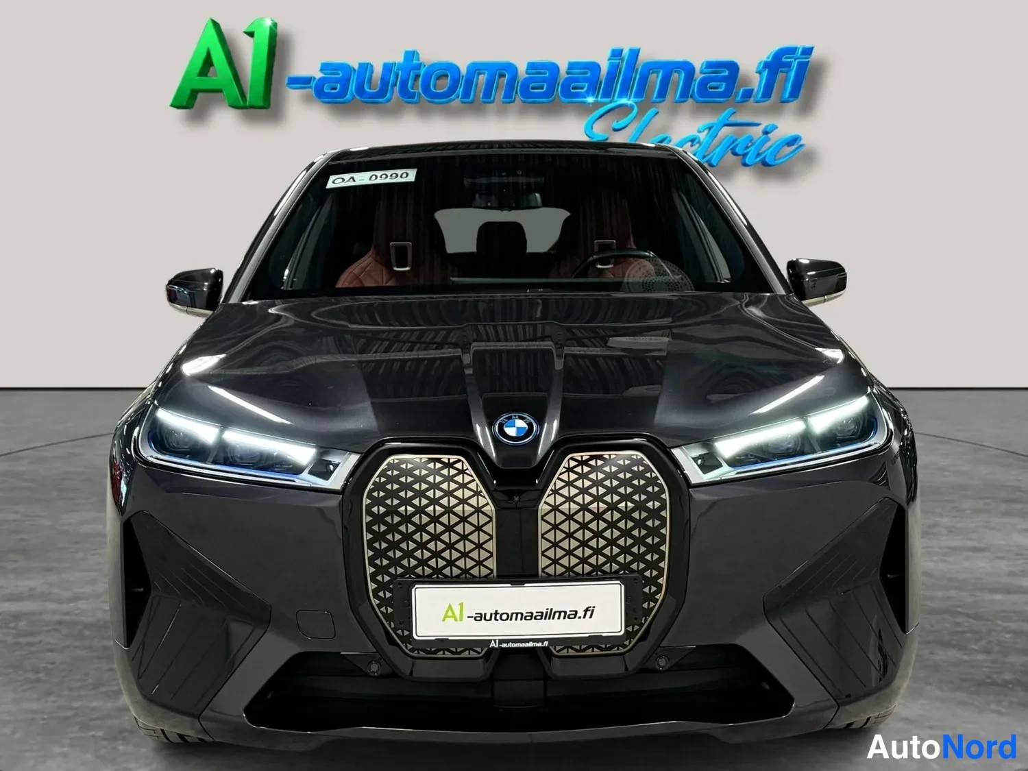 Edestä: BMW iX, tummanharmaa suora etunäkymä, suljettu etusäleikkö ja LED-ajovalot.