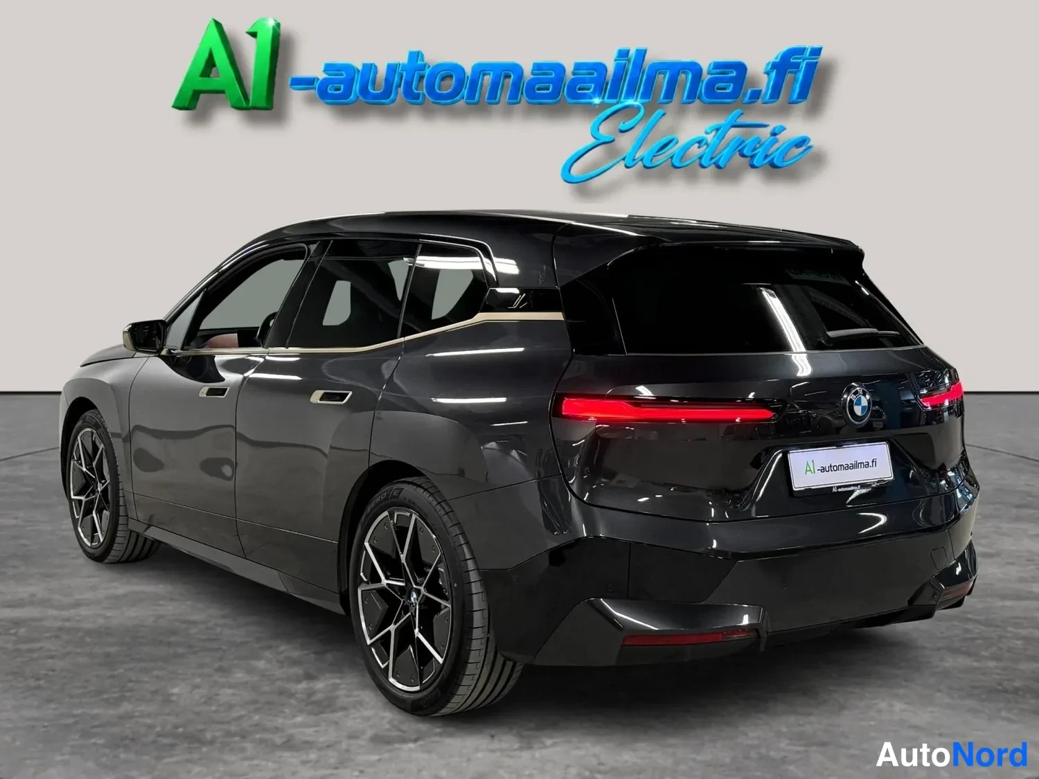 Takaviisto: BMW iX, tummanharmaa takakulmakuva vasemmalta, vaaka-asentoiset takavalot ja katkaisijan kattospoileri.