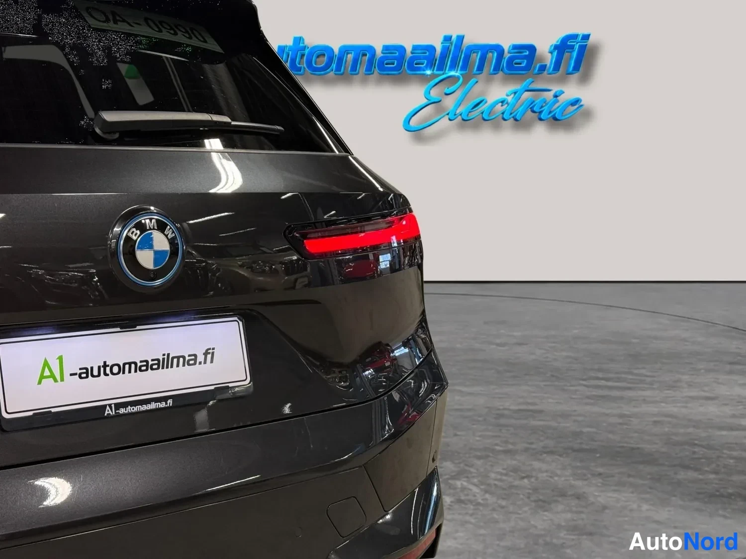 Muu: Auton takaosa lähikuvassa: BMW-merkki, punainen takavalo ja rekisterikilpi mainostekstillä A1-automaaailma.fi.