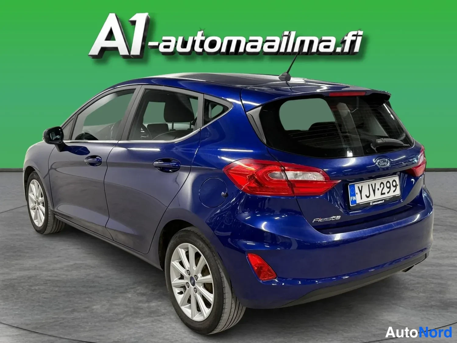 Takaviisto: Ford Fiesta takaviisto kuvattuna, tummansininen koripinta, rekisterikilpi ja Fiesta-merkintä näkyvissä.