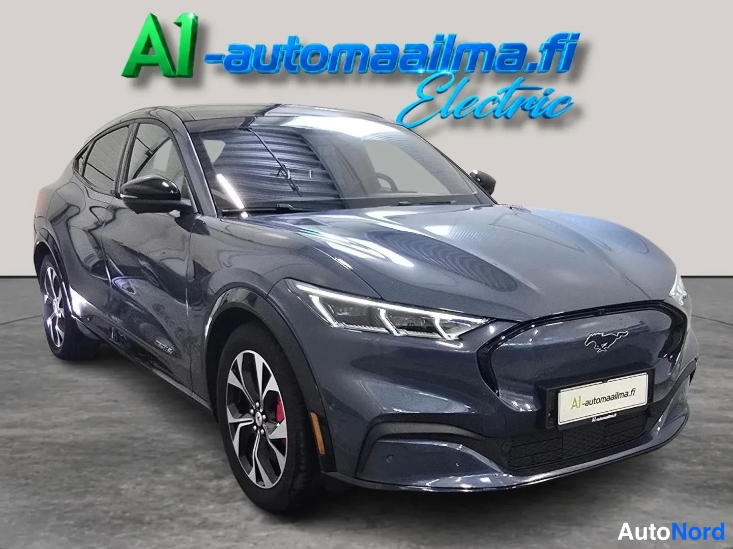 Etuviisto, nokka oikealle: Tummansinisen Ford Mustang Mach-E:n etukulma kuvasssa oikealta, kylki ja etupää näkyvissä.