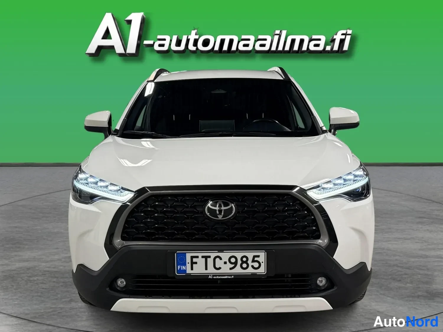 Edestä: Valkoisen Toyota Corolla Crossin etunäkymä, rekisterikilpi.