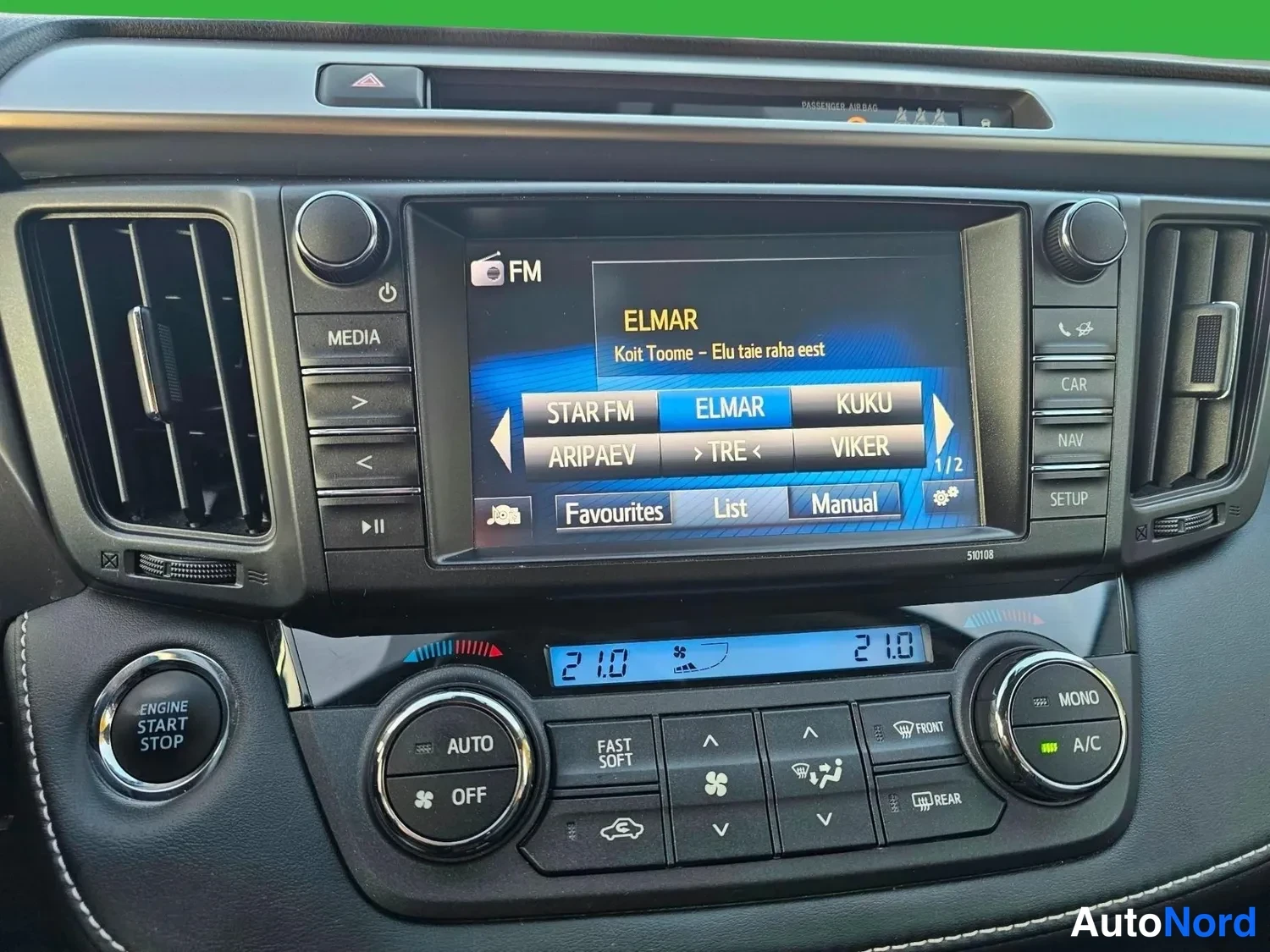 Yksityiskohta: Kojelauta- ja multimedialaitteiden lähikuva: kosketusnäyttö näyttää FM-radiota (ELMAR), keskellä ilmastointipaneeli (AUTO, OFF, 21.0 molemmin puolin), vasemmall