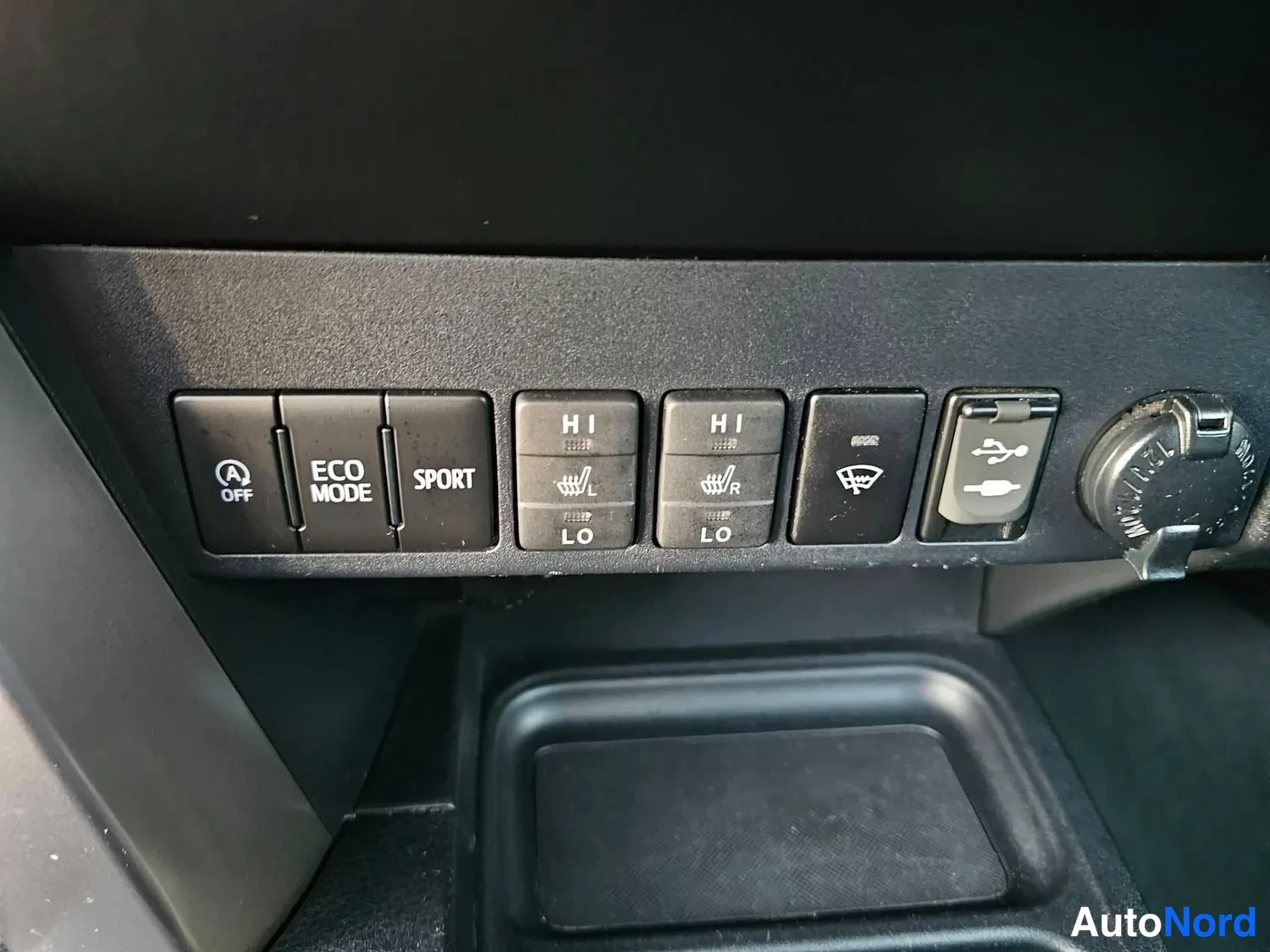 Yksityiskohta: KeskiC-panelin alapuolista kytkinriviä: A-OFF, ECO MODE, SPORT, istuinten lämmitys H/L vasen ja oikea, sähköisesti taittuva peili-symboli, USB-portti ja 12V-pis